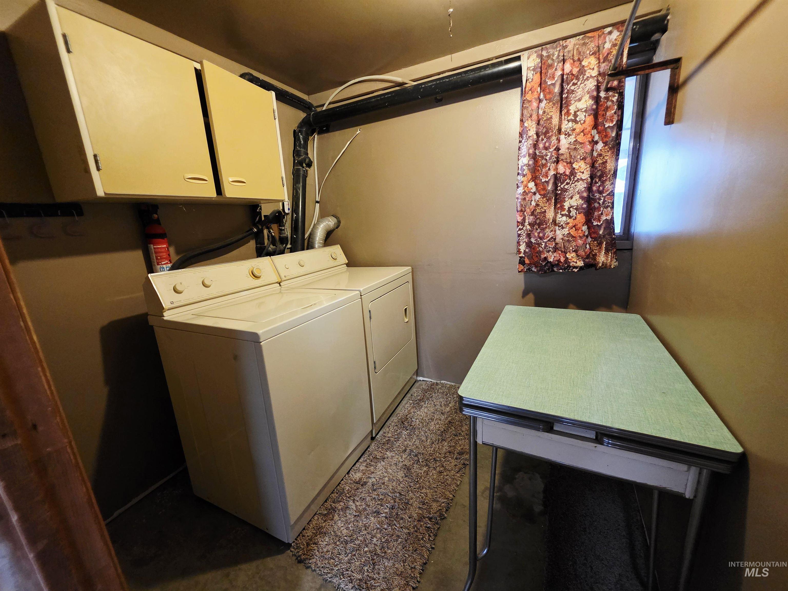 Laundry area featuring separate washer and dryer, cabinet space, and unfinished concrete flooring