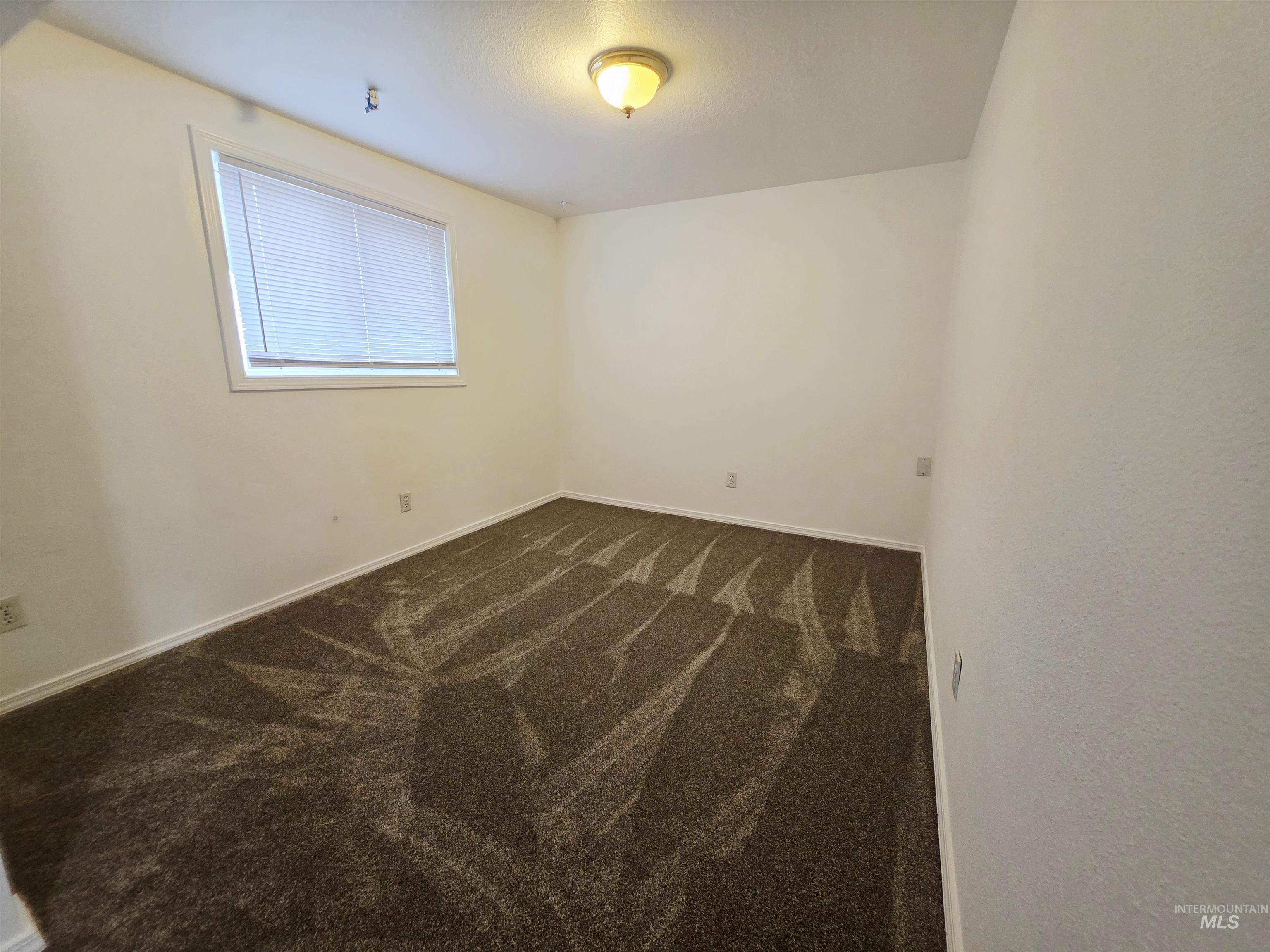 Unfurnished room featuring dark carpet and a textured ceiling