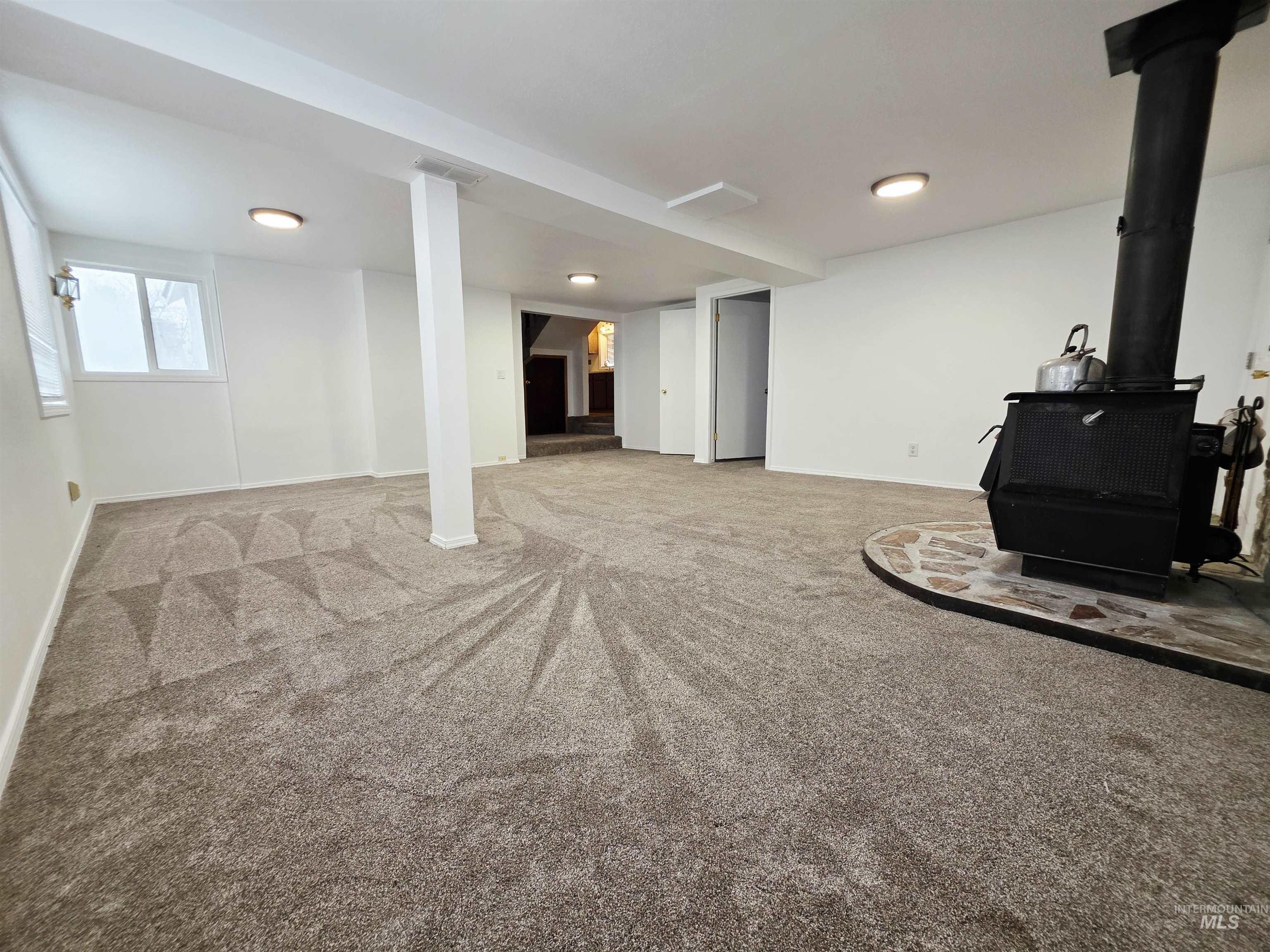 Basement featuring a wood stove and light colored carpet