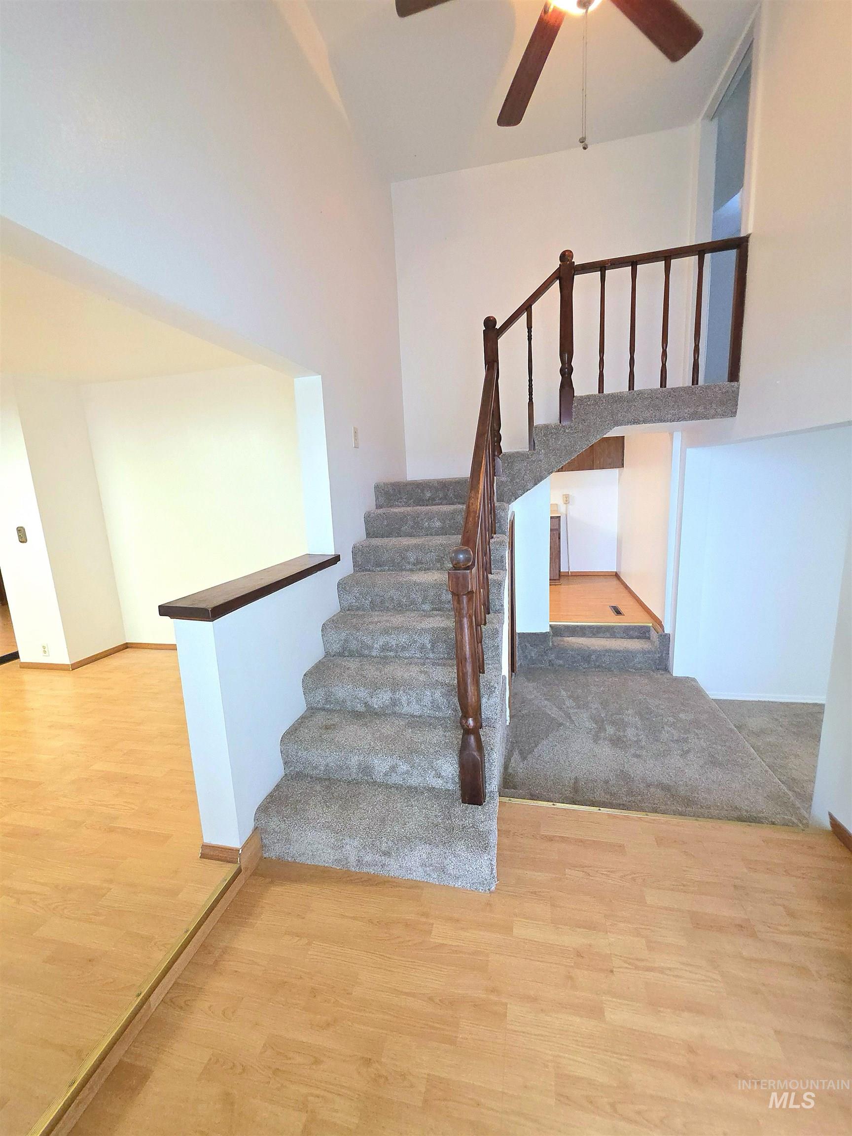 Stairs with wood finished floors and ceiling fan