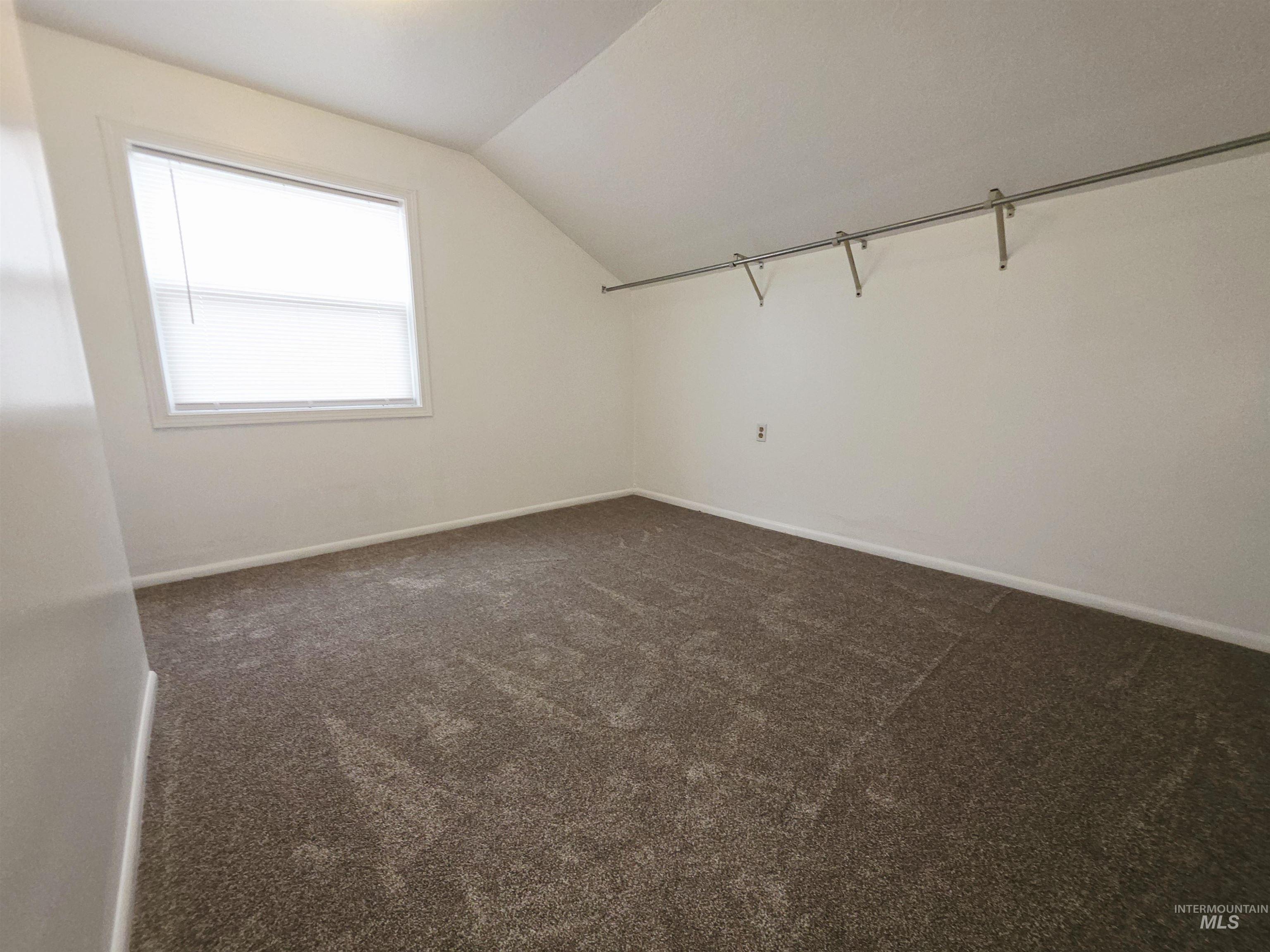 Bonus room with lofted ceiling and dark carpet