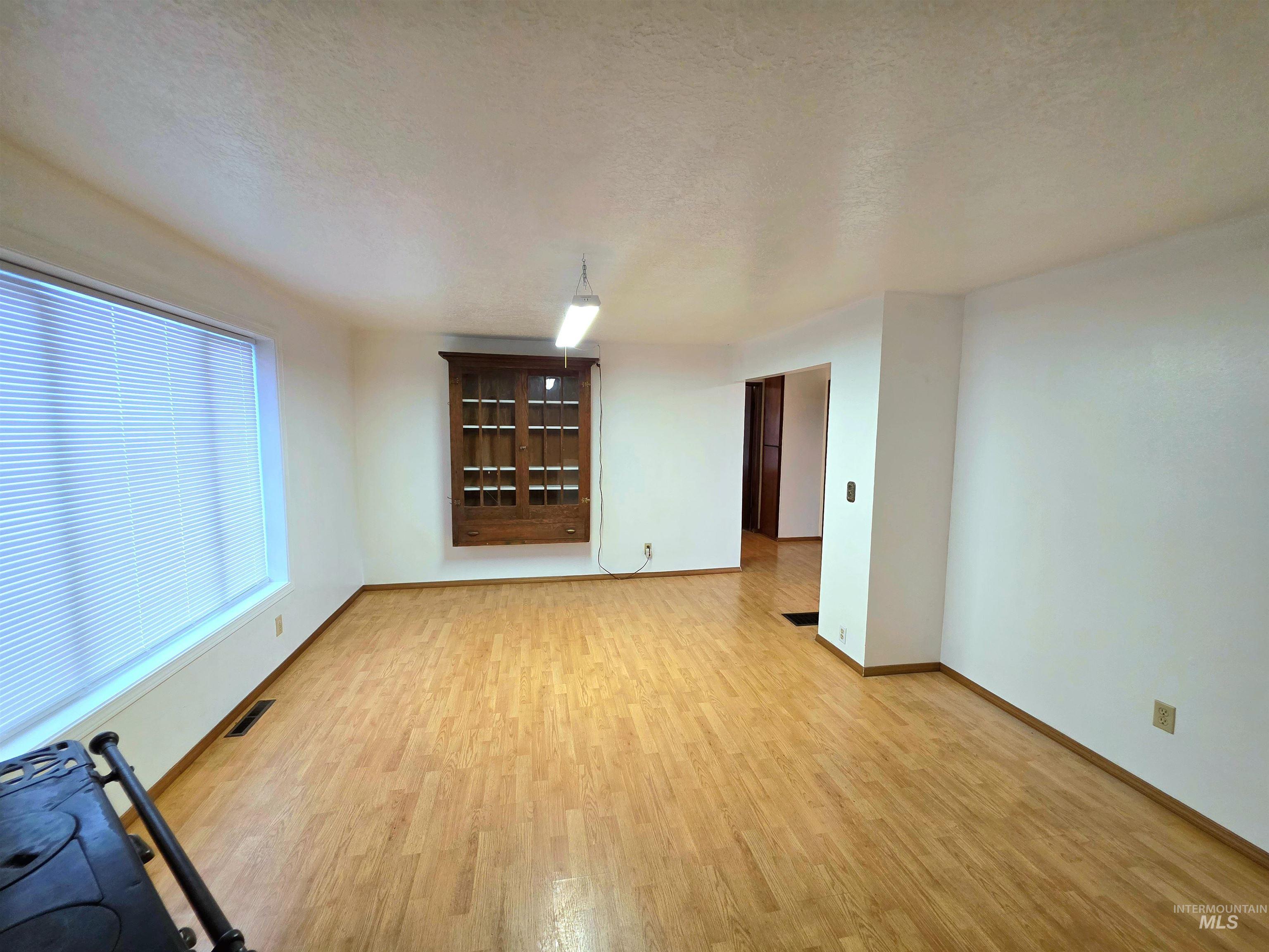Unfurnished living room featuring a textured ceiling and light wood finished floors