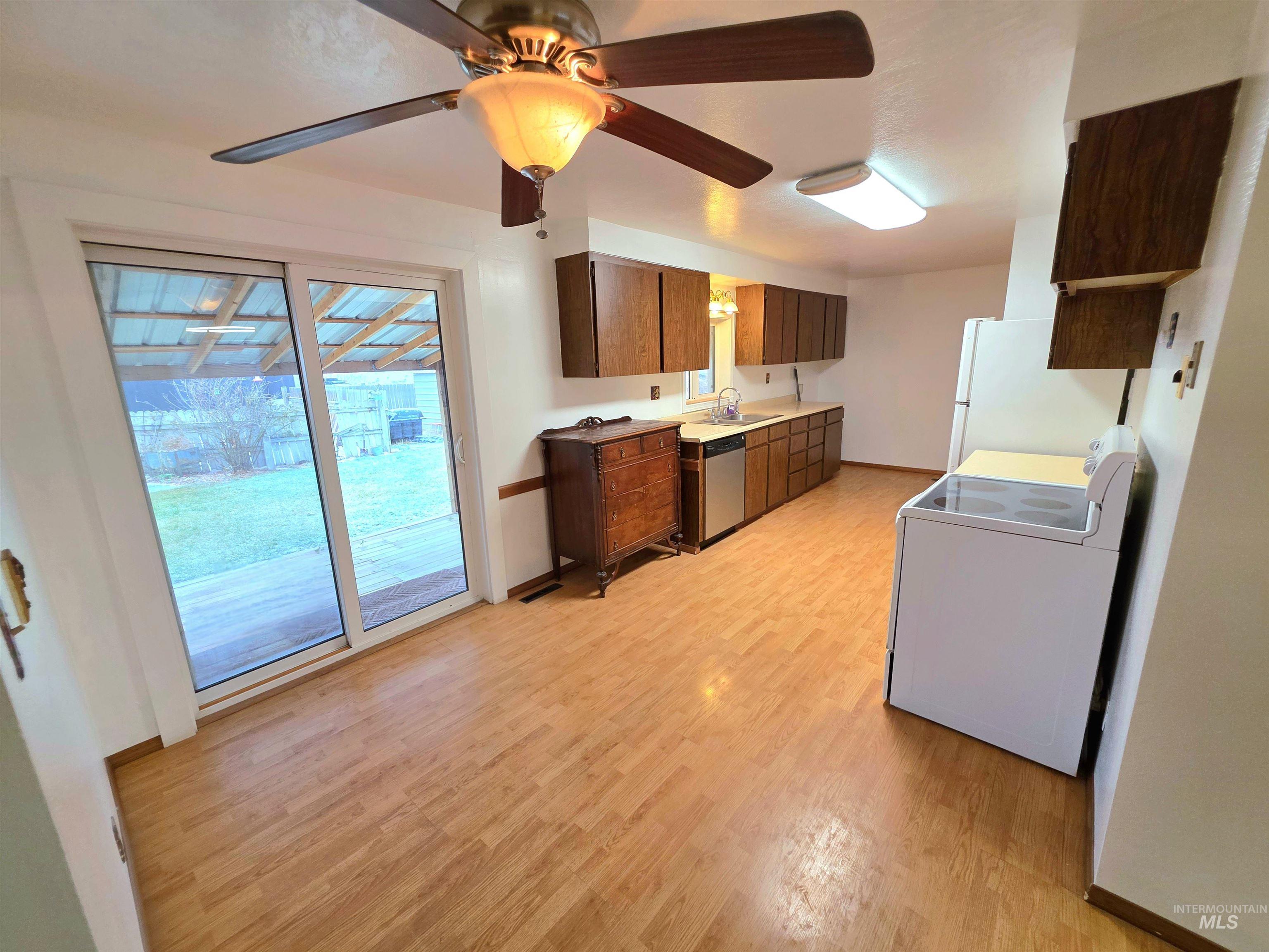 Kitchen featuring white appliances, light countertops, light wood-style flooring, and ceiling fan