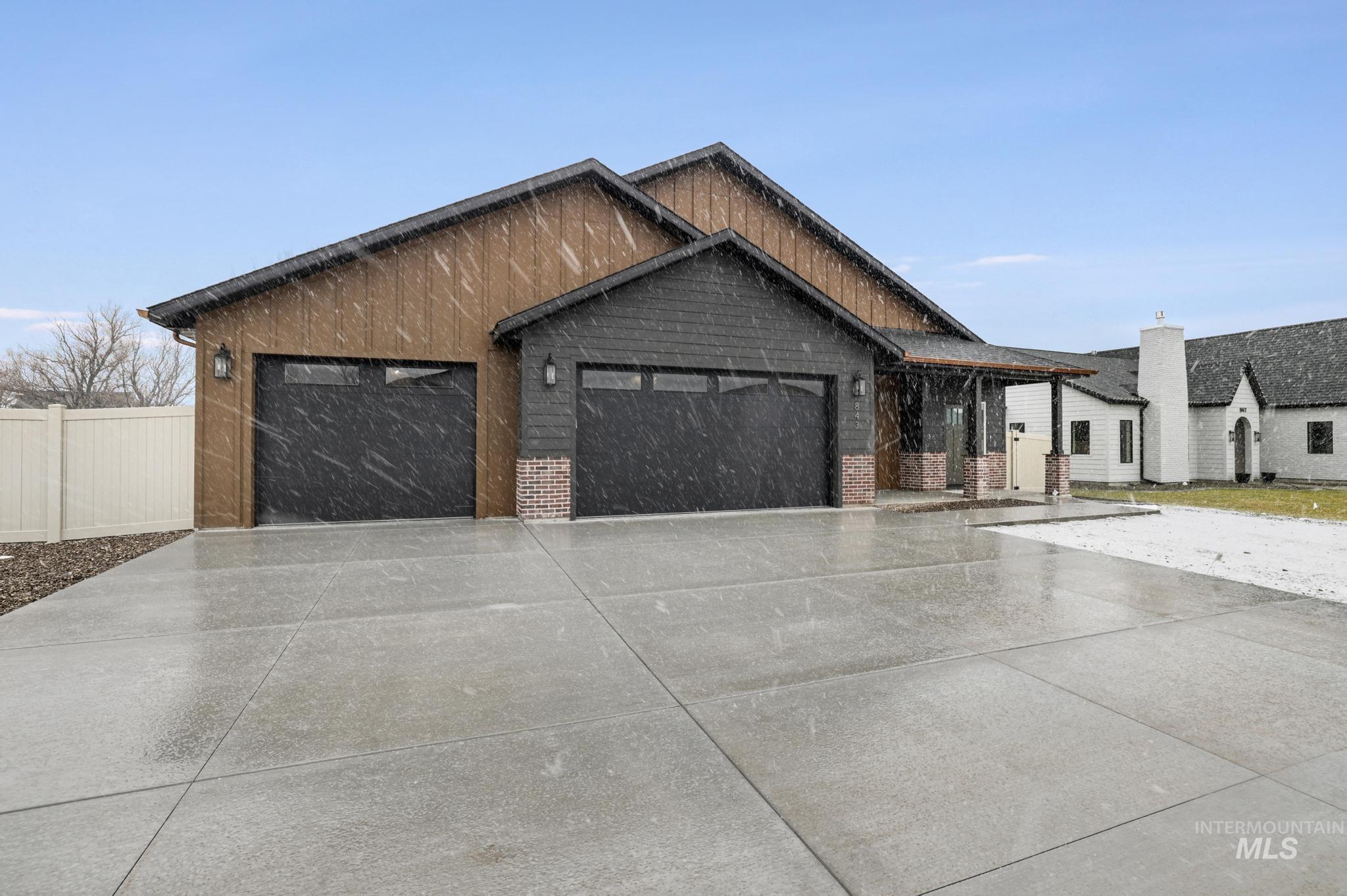 View of front of property featuring an attached garage, concrete driveway, and brick siding