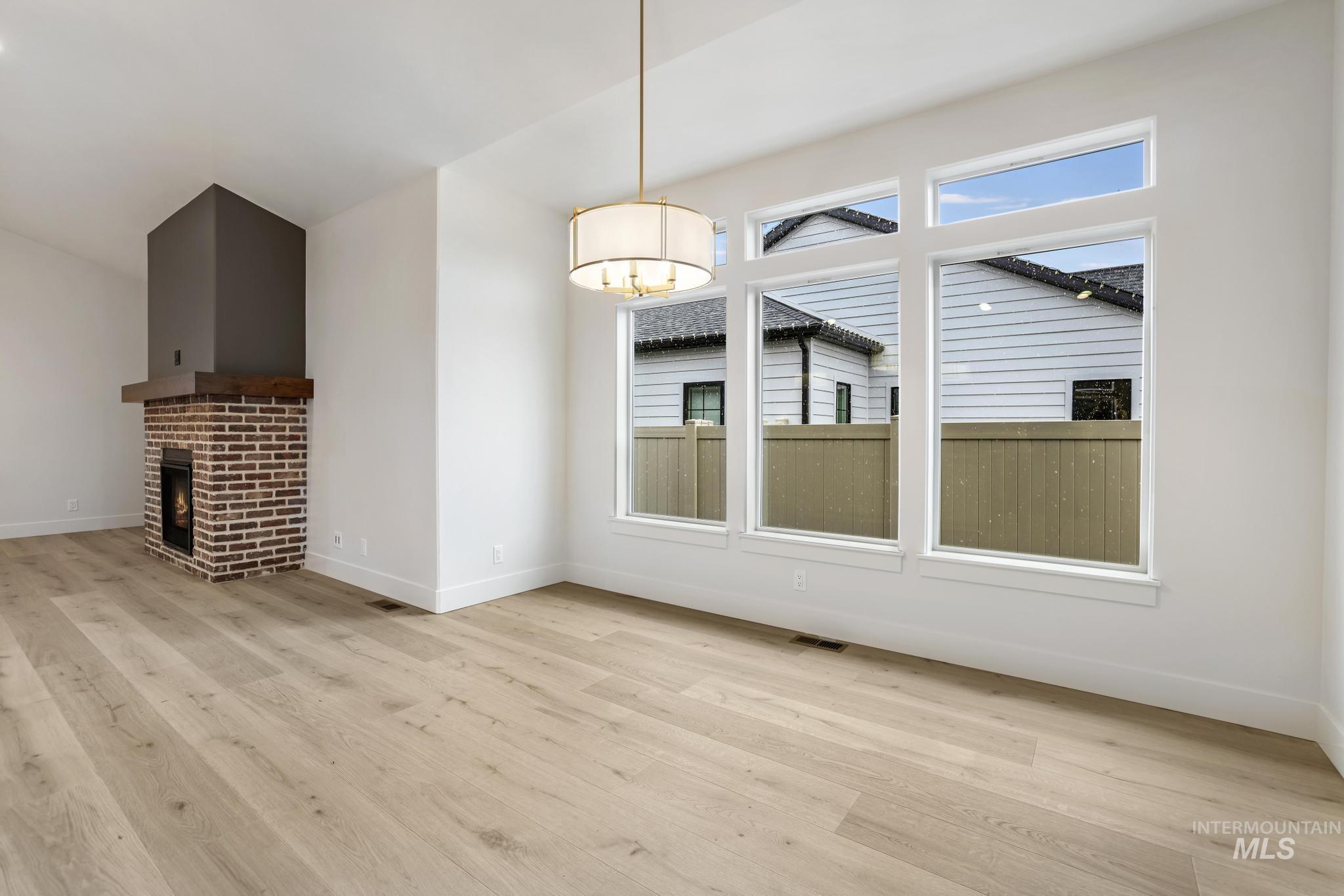 Unfurnished dining area featuring light wood-style floors and a brick fireplace