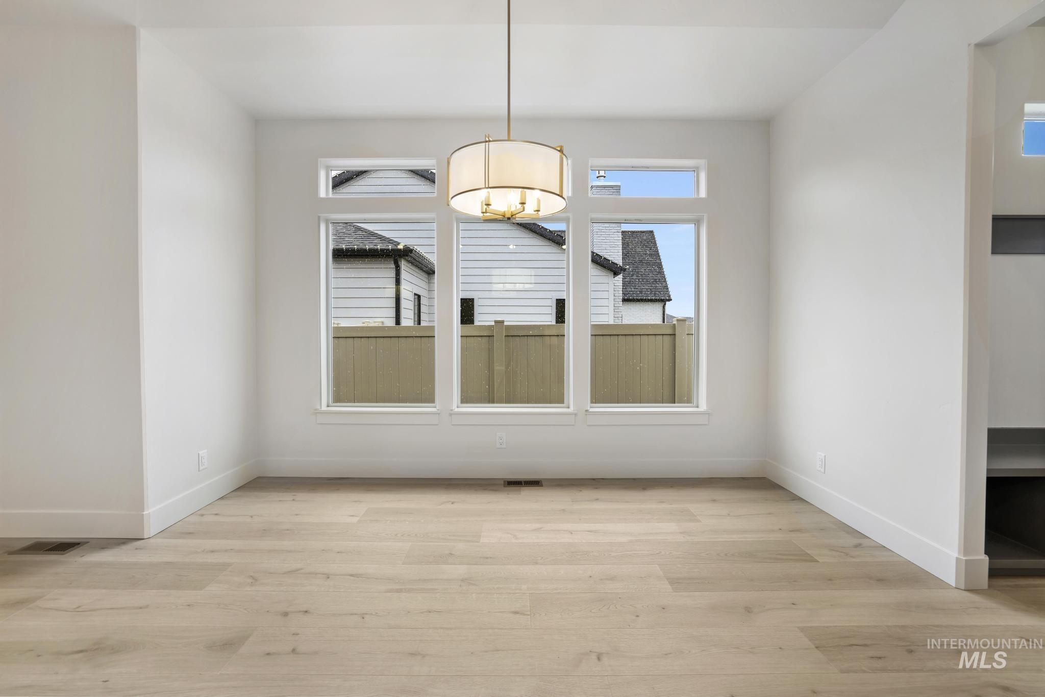 Unfurnished dining area featuring light wood finished floors and a chandelier