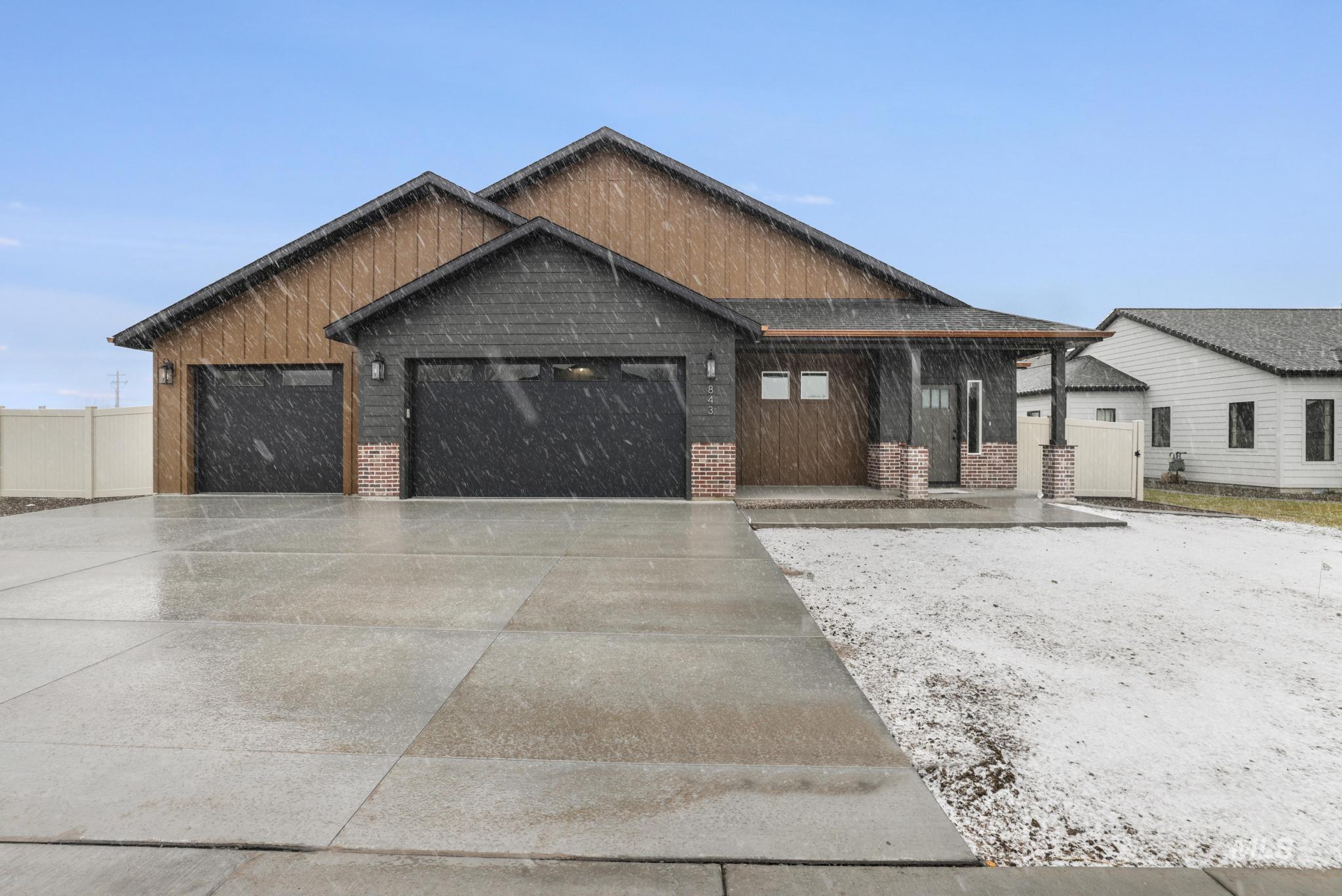 View of front of property featuring a porch, driveway, a garage, and brick siding