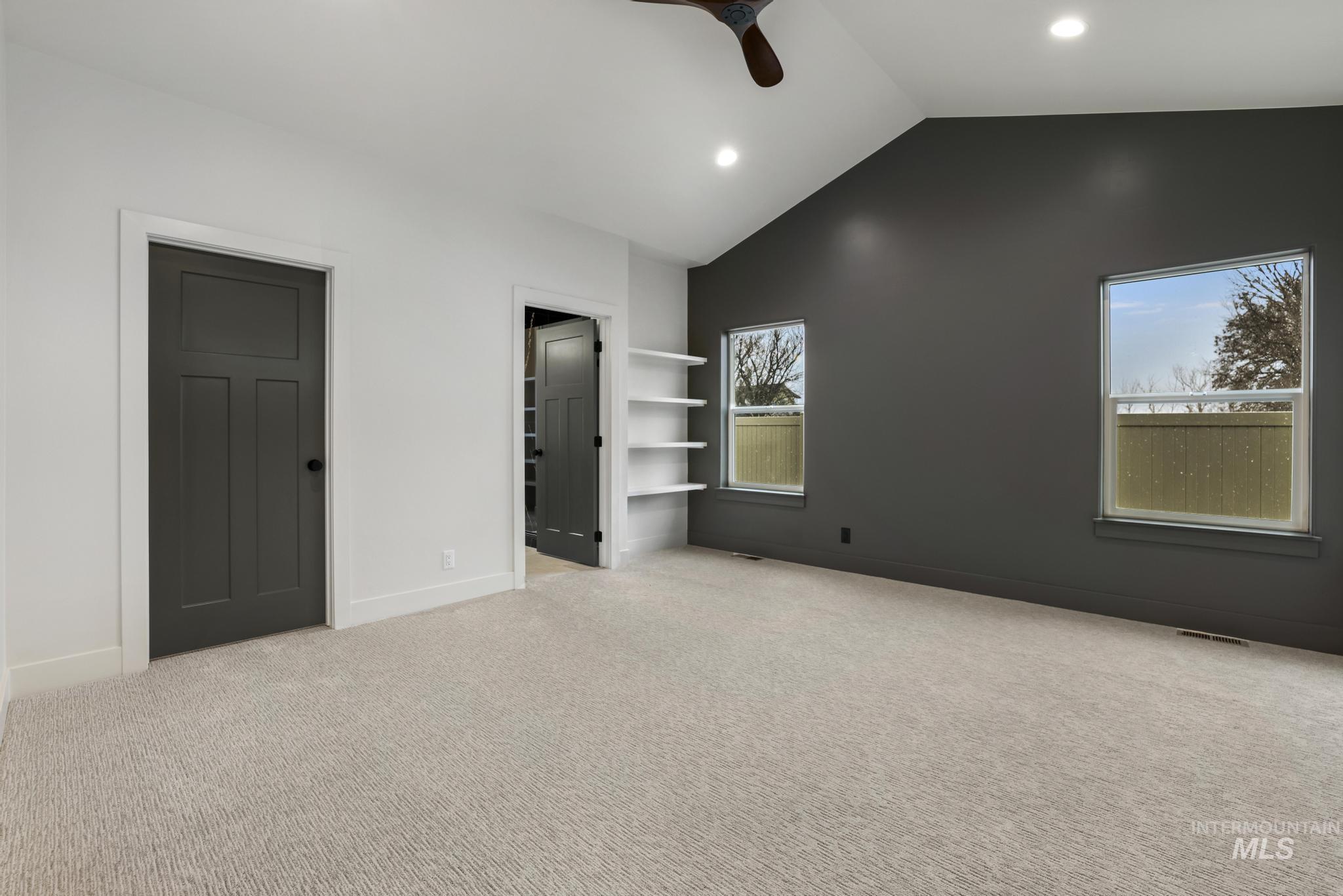 Unfurnished bedroom featuring lofted ceiling, light carpet, ceiling fan, a spacious closet, and recessed lighting