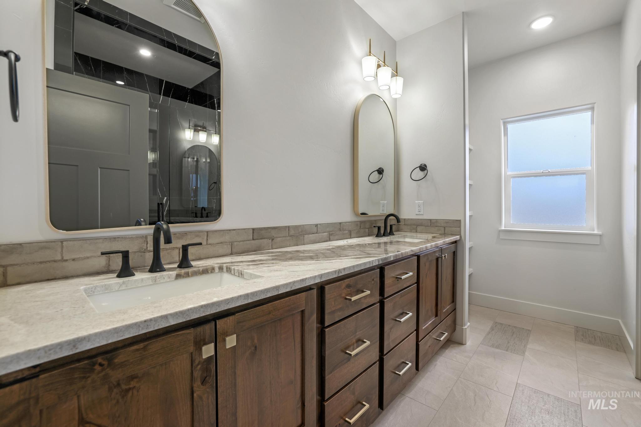Bathroom with double vanity, light tile patterned floors, recessed lighting, and a shower with shower door