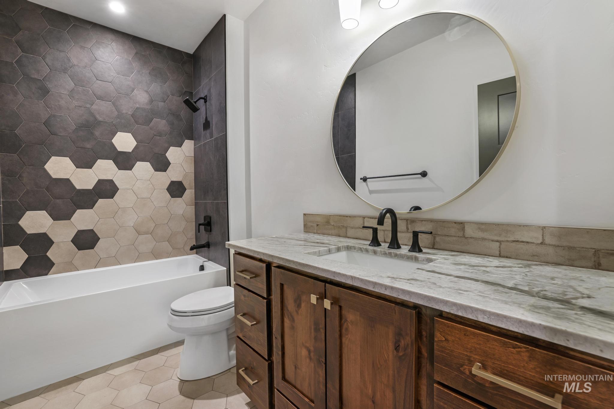 Bathroom with shower / bath combination, vanity, and light tile patterned flooring