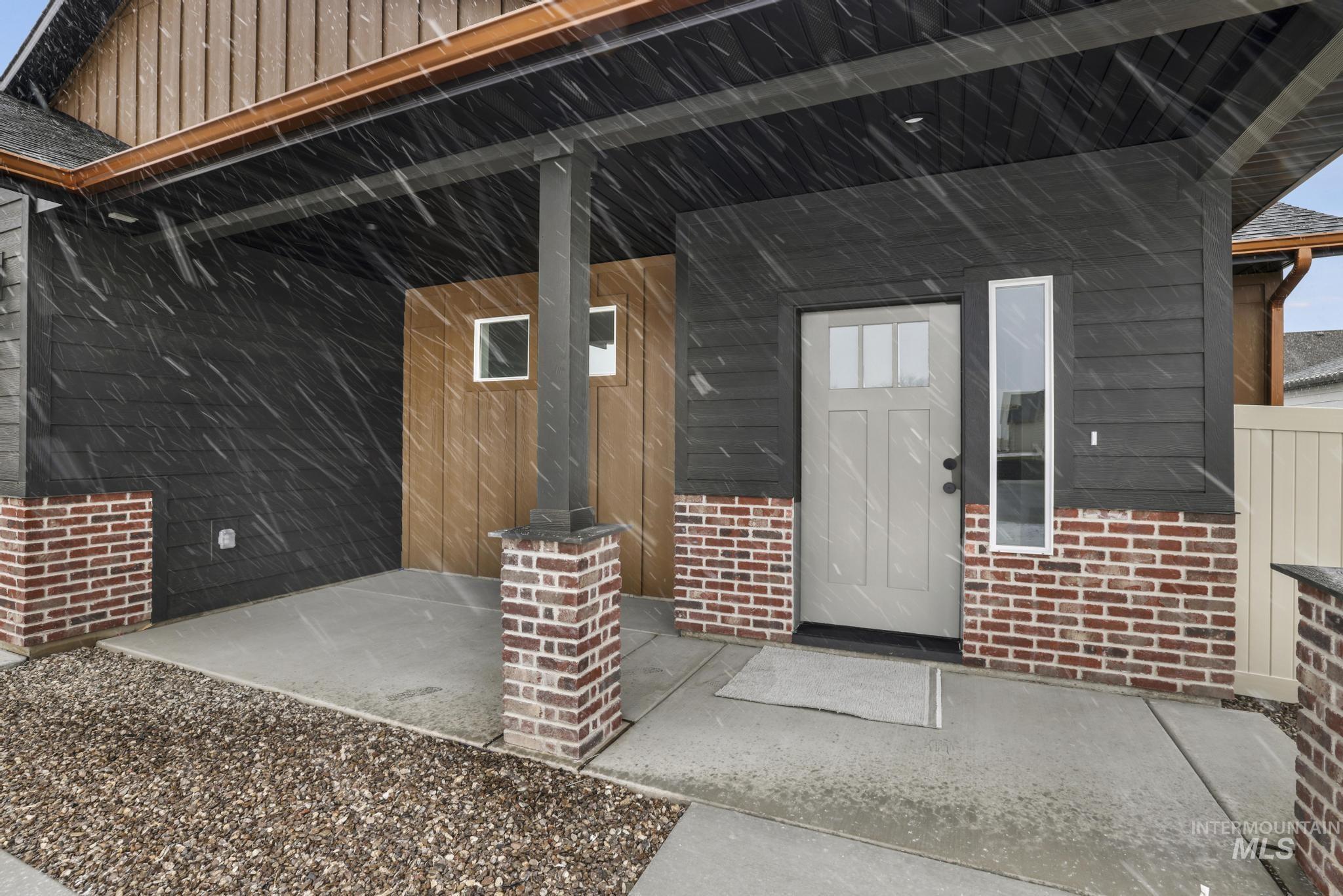 Entrance to property with a porch, brick siding, and board and batten siding