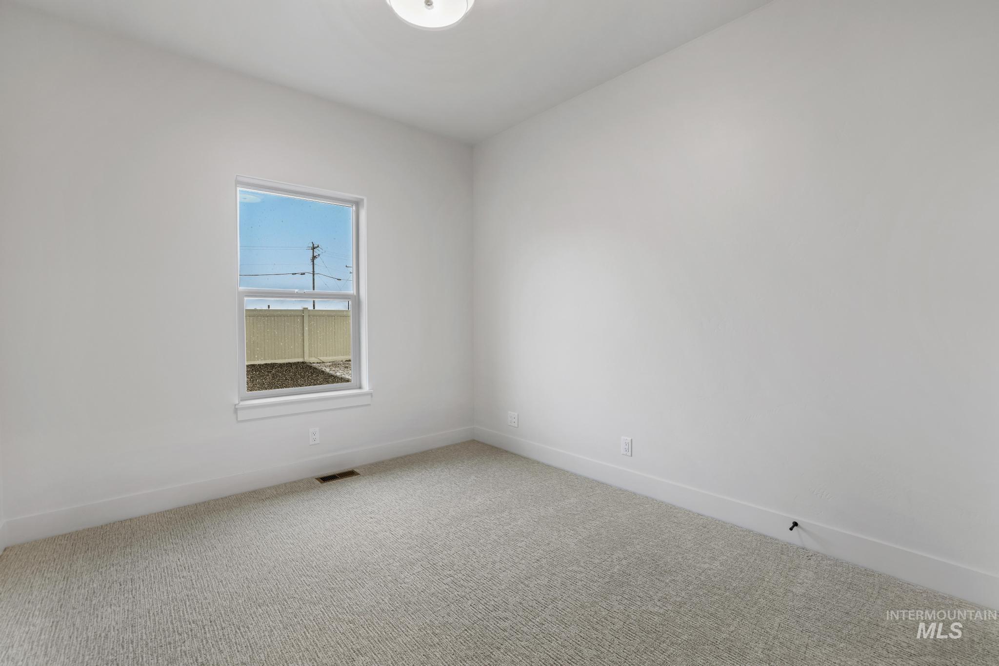 Spare room featuring carpet flooring and baseboards