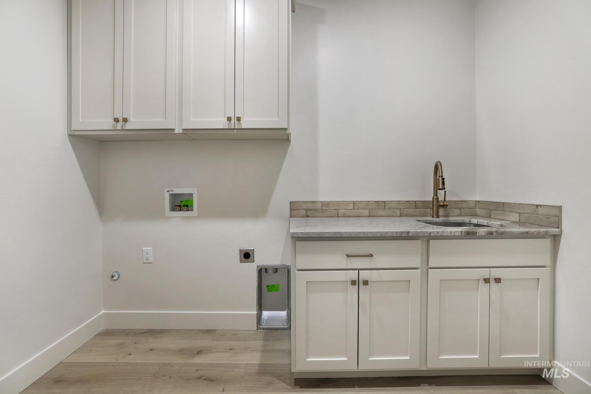 Washroom with cabinet space, hookup for a washing machine, light wood-style floors, and electric dryer hookup