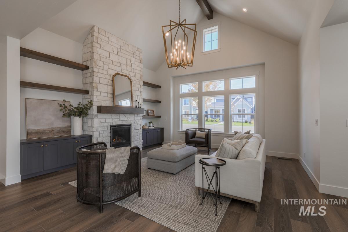 Living room featuring beamed ceiling, high vaulted ceiling, plenty of natural light, a stone fireplace, and dark wood finished floors