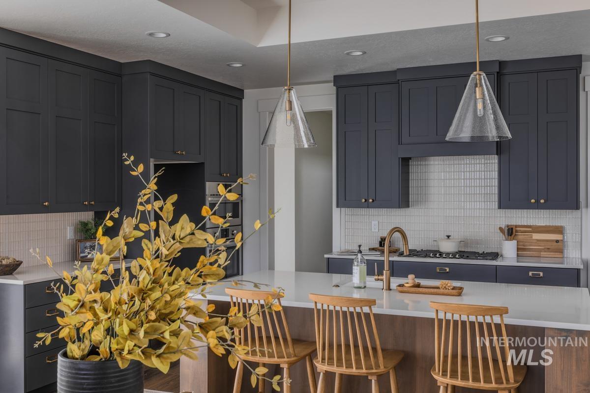 Kitchen with backsplash, light stone countertops, decorative light fixtures, and recessed lighting