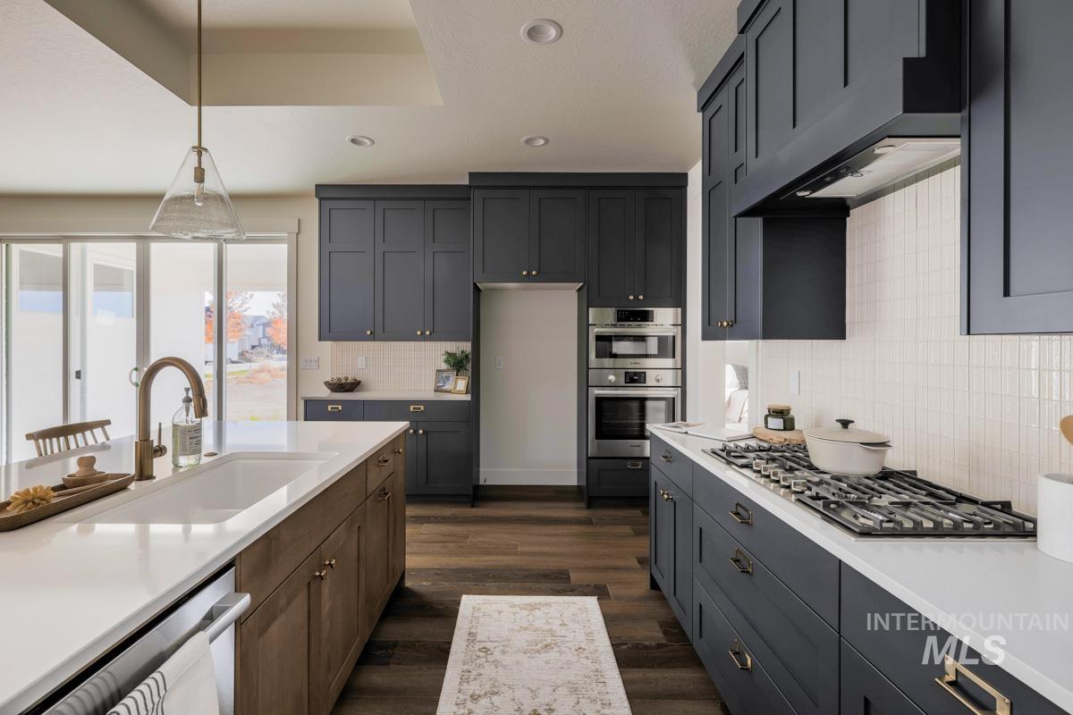 Kitchen with dark wood-style floors, recessed lighting, pendant lighting, appliances with stainless steel finishes, and under cabinet range hood