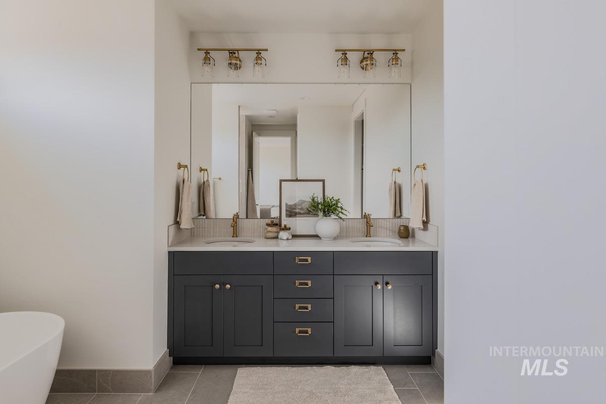 Full bathroom with double vanity, light tile patterned floors, and a freestanding bath
