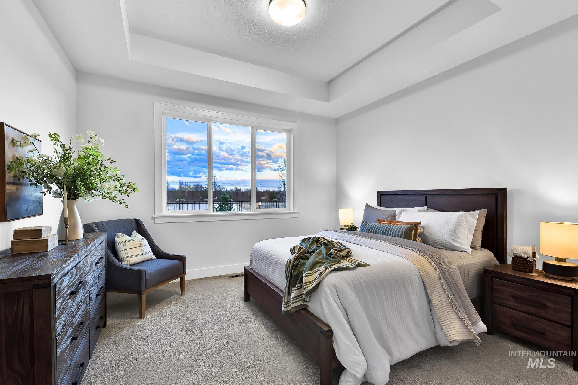 Bedroom featuring a tray ceiling and light colored carpet