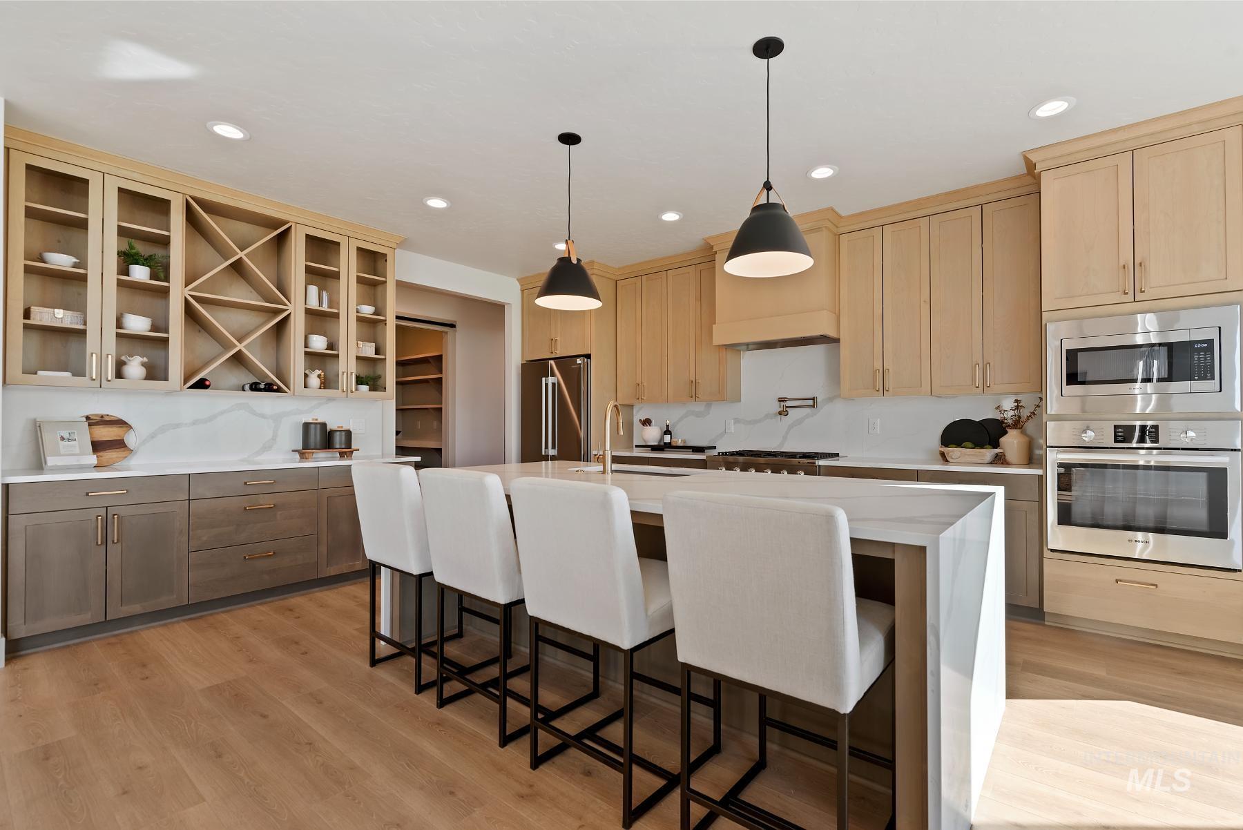Kitchen featuring appliances with stainless steel finishes, light stone counters, a center island with sink, light brown cabinetry, and recessed lighting