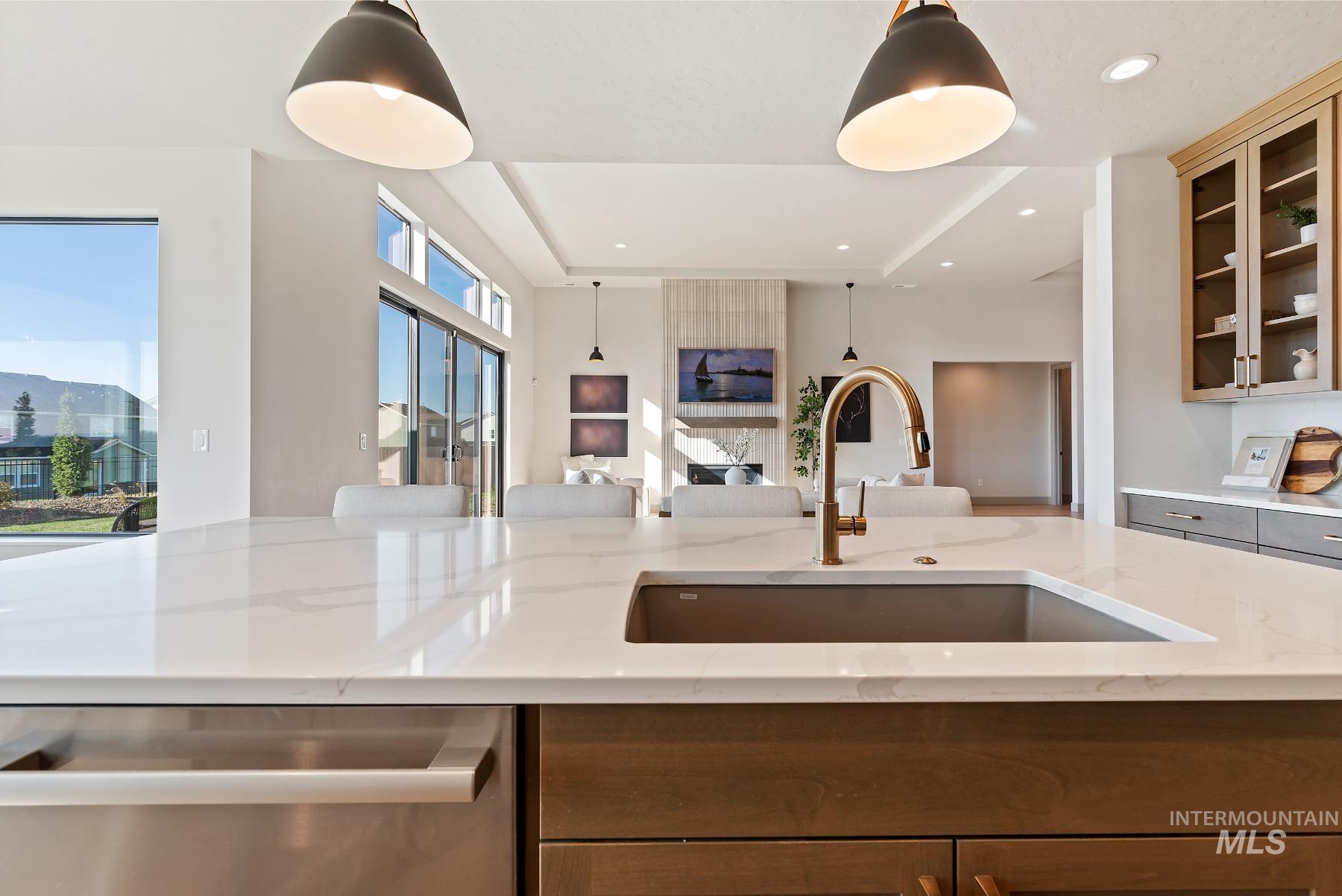 Kitchen with dishwasher, glass insert cabinets, light stone counters, pendant lighting, and recessed lighting