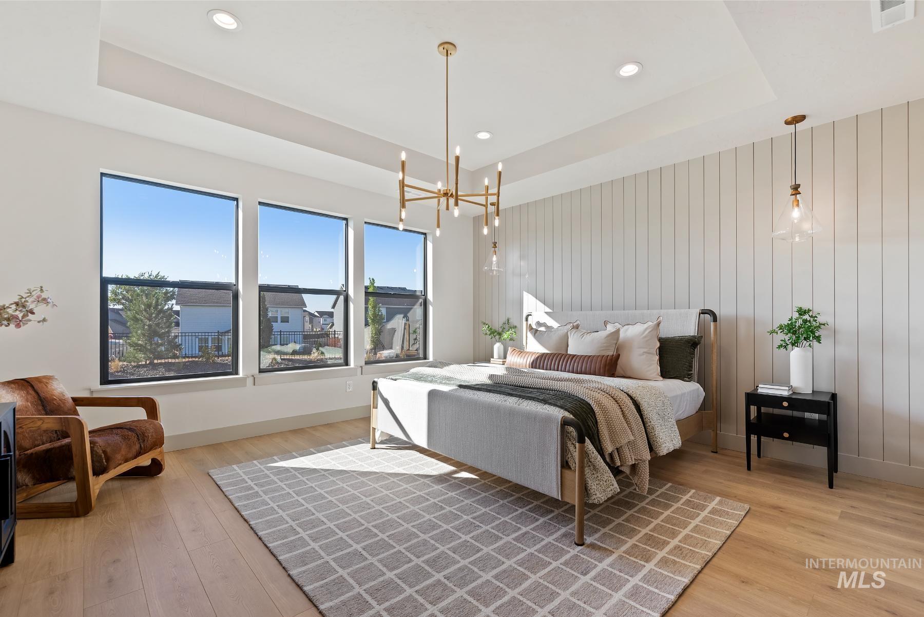 Bedroom with a raised ceiling, a chandelier, light wood-style floors, wood walls, and recessed lighting