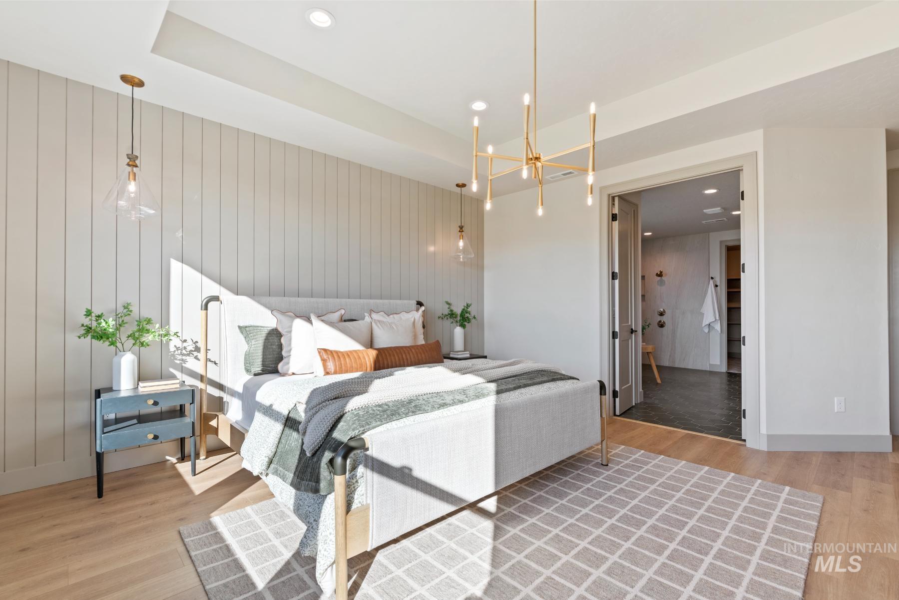 Bedroom featuring a chandelier, recessed lighting, light wood-style floors, wooden walls, and connected bathroom