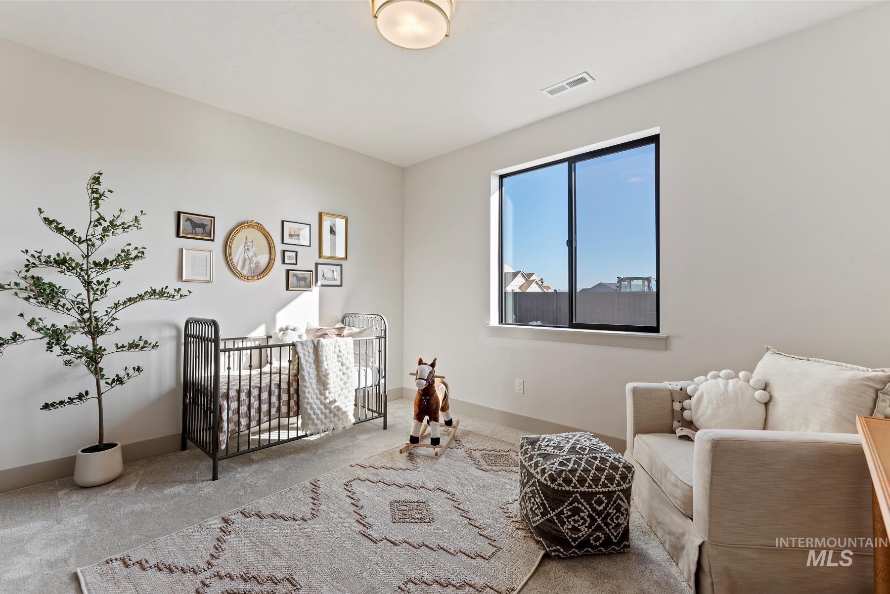 Bedroom featuring a crib and carpet floors