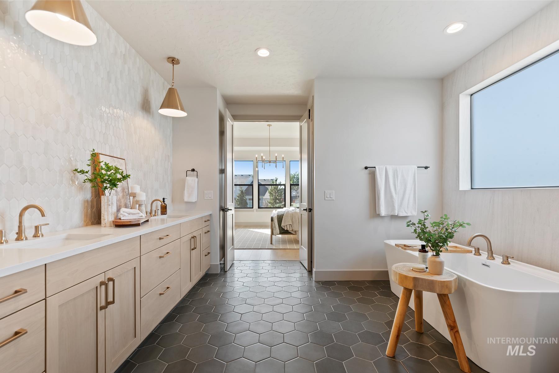 Full bathroom featuring double vanity, a soaking tub, recessed lighting, a chandelier, and an accent wall