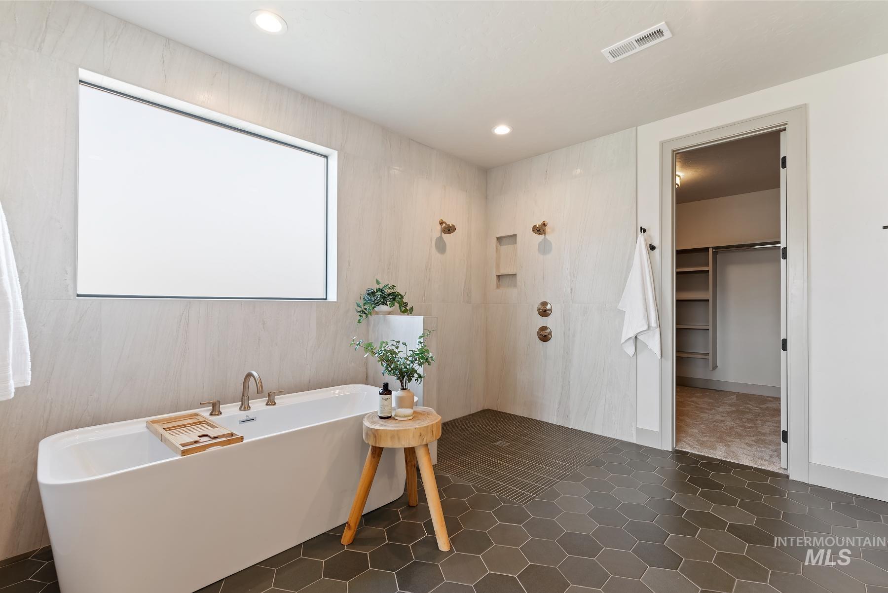 Full bathroom with a spacious closet, a freestanding tub, recessed lighting, a shower, and dark tile patterned floors