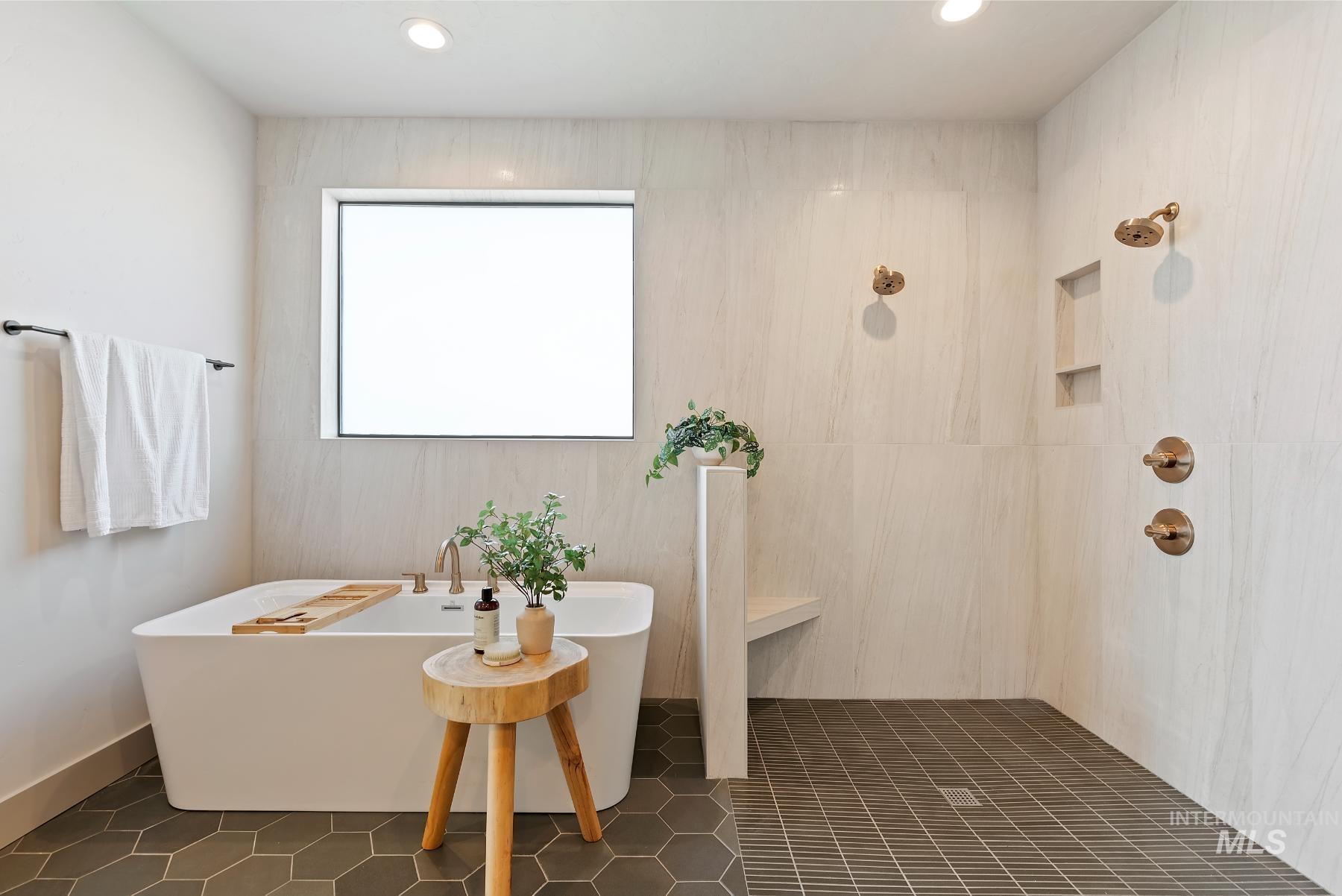 Full bath featuring recessed lighting, a freestanding tub, a tile shower, and dark tile patterned flooring