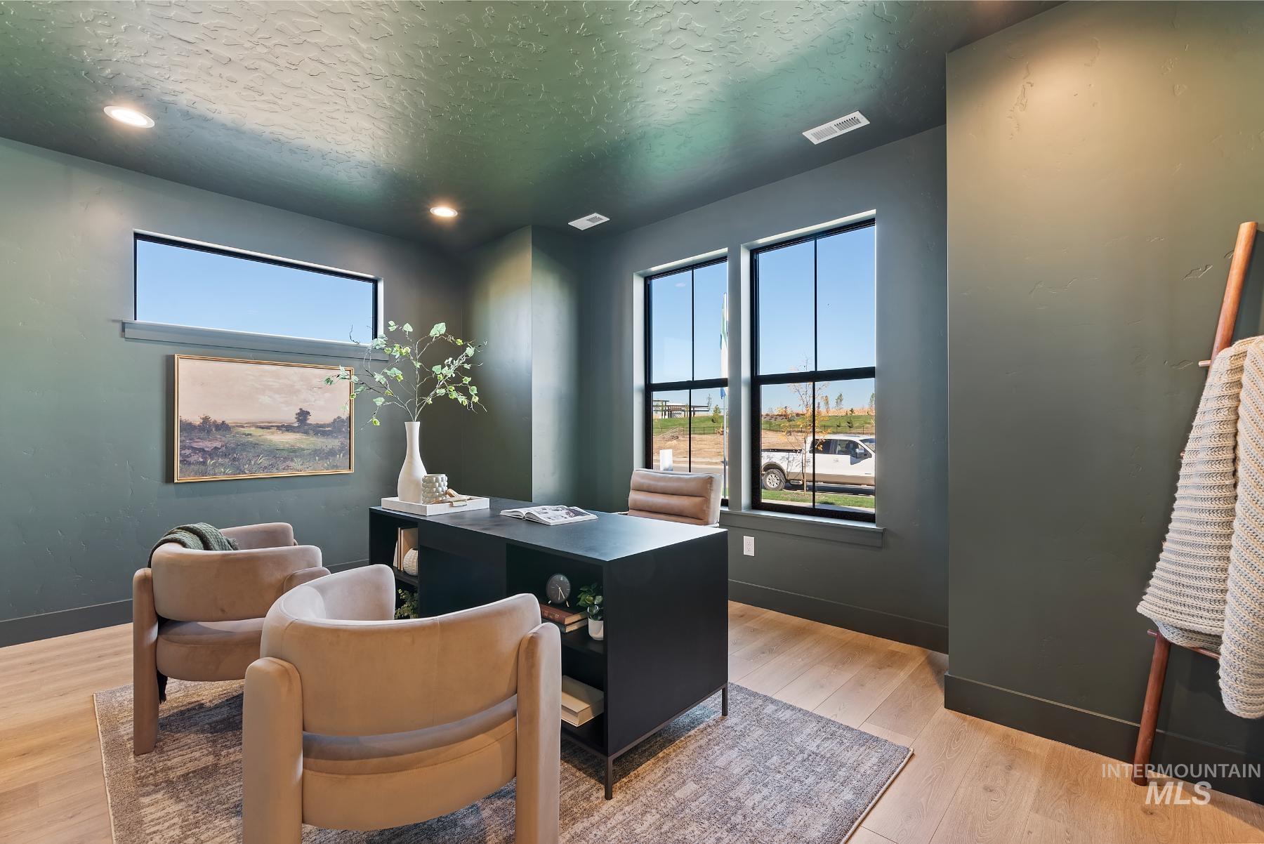 Home office with light wood-style floors, a textured ceiling, and recessed lighting