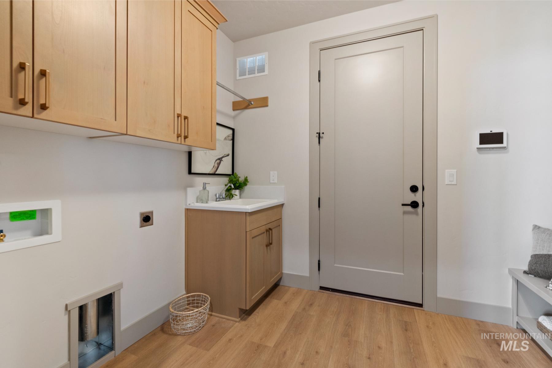 Washroom featuring cabinet space, hookup for an electric dryer, washer hookup, and light wood-type flooring