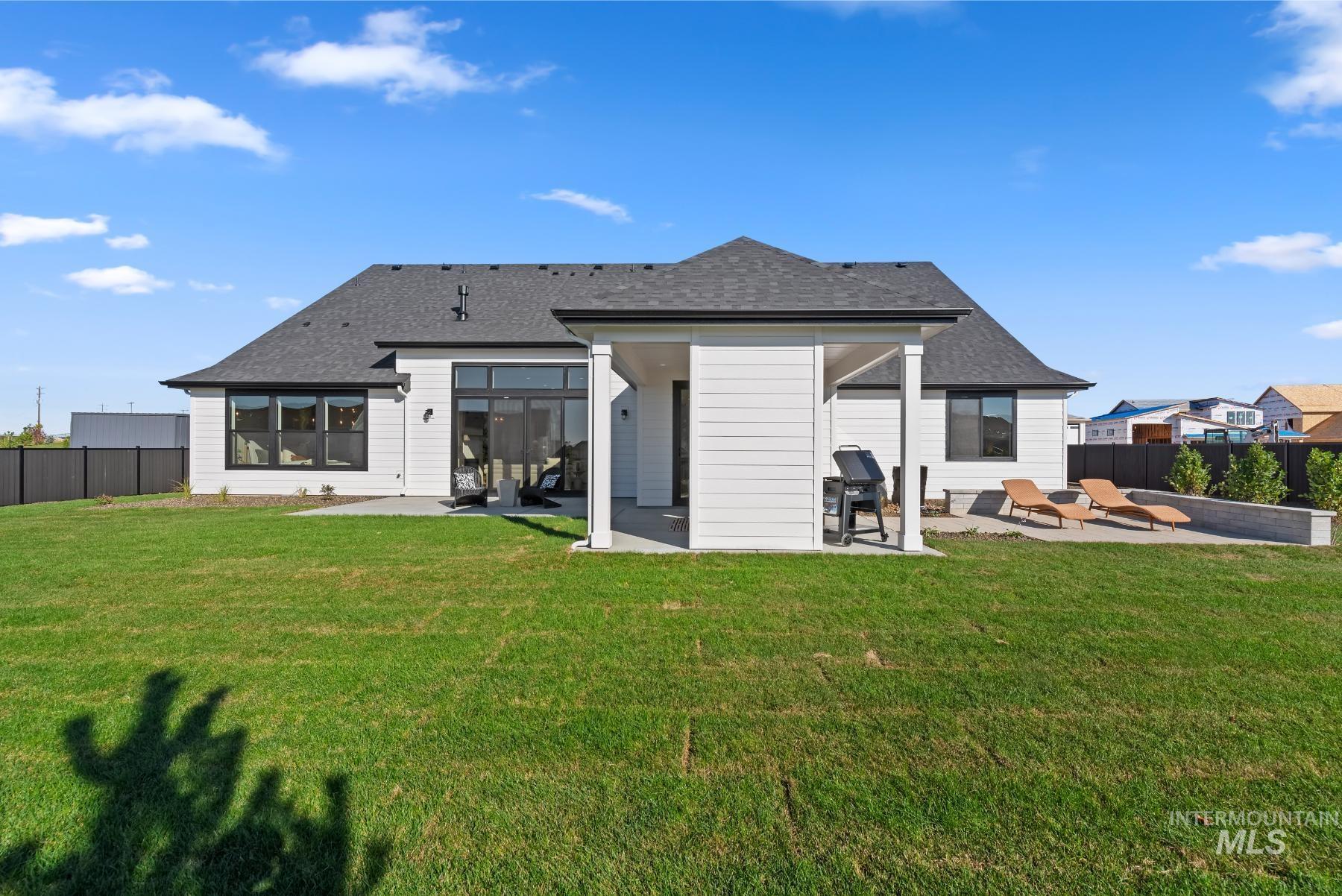 Rear view of property featuring a patio, a fenced backyard, and roof with shingles