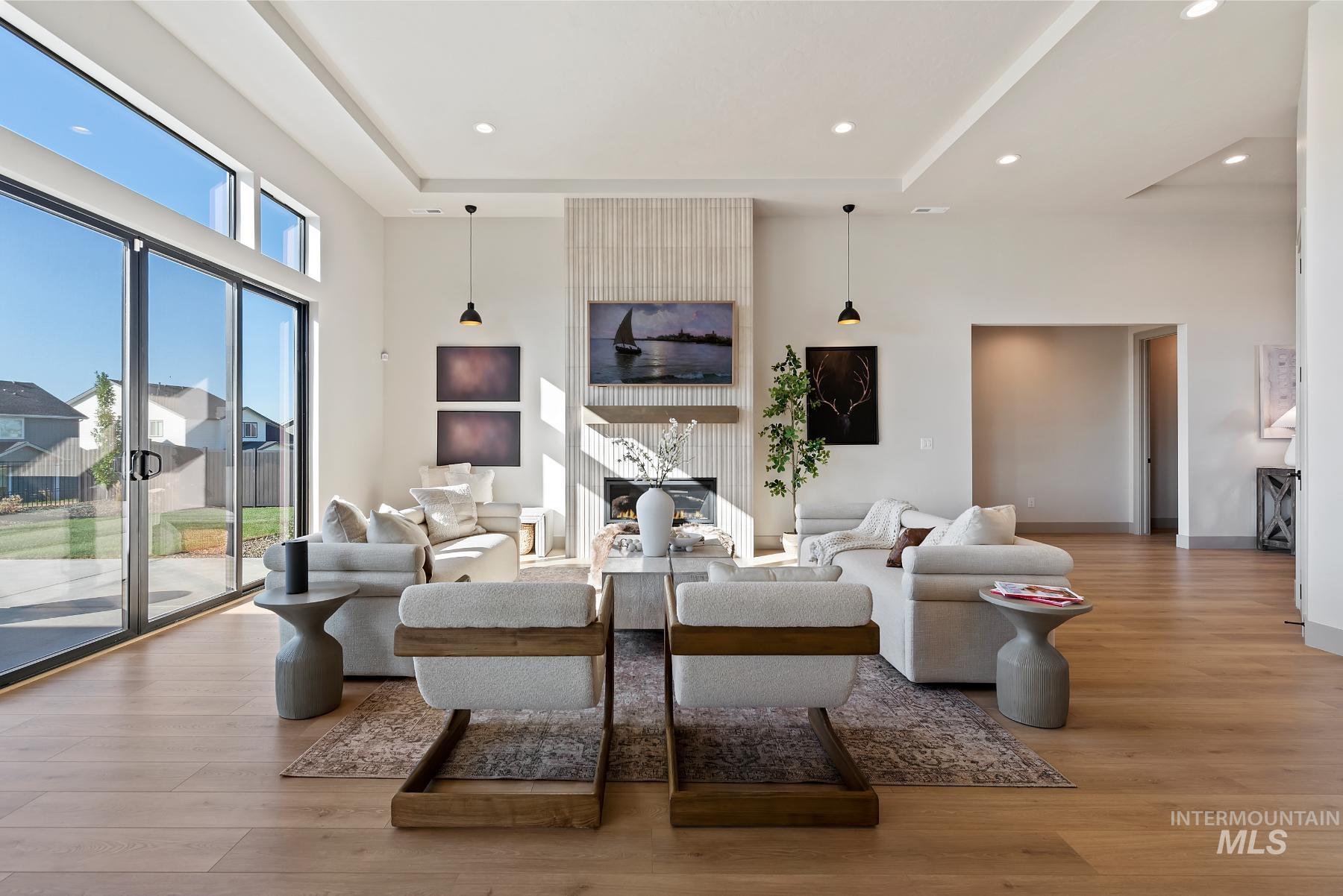 Living room featuring a large fireplace, light wood-style floors, recessed lighting, and a towering ceiling