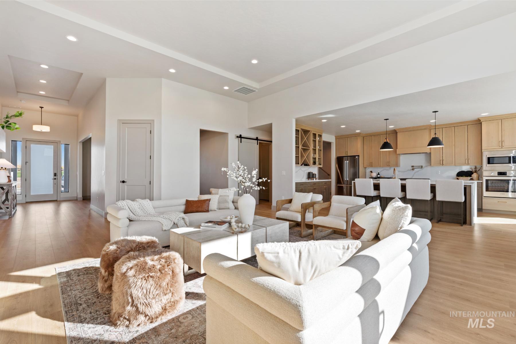 Living area featuring recessed lighting, a barn door, light wood-style floors, a high ceiling, and french doors