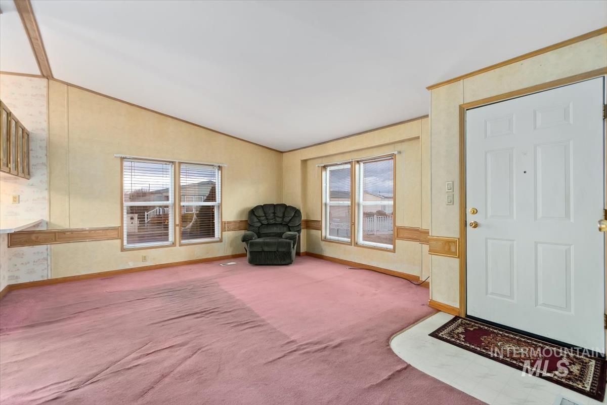 Foyer with vaulted ceiling, carpet, and wallpapered walls