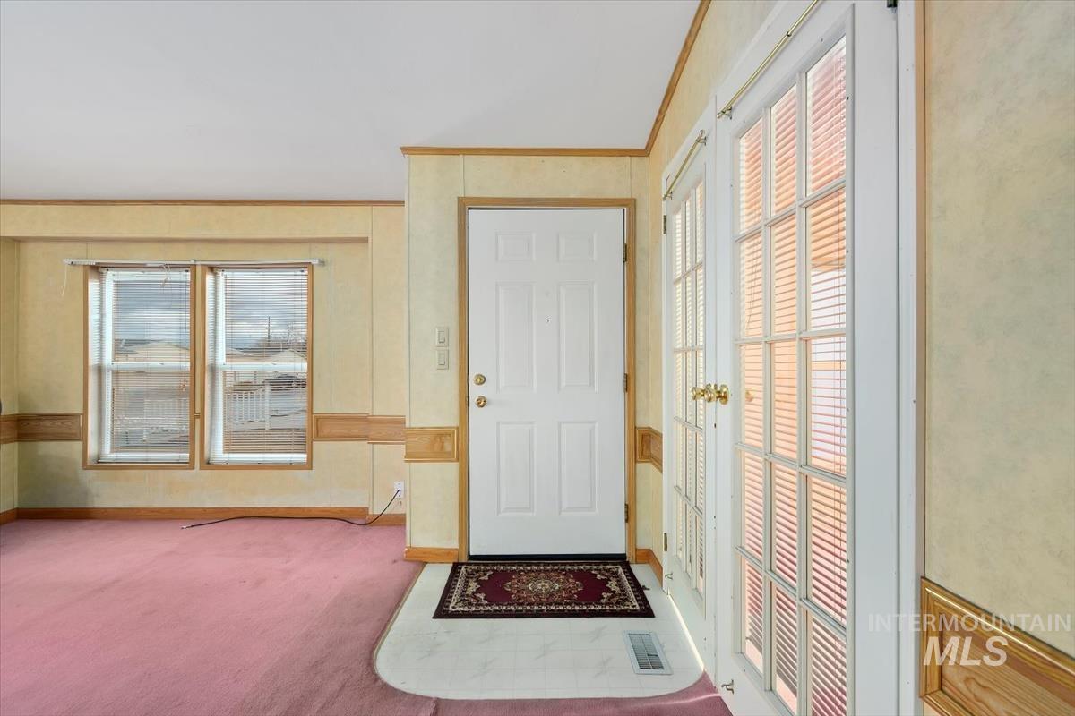 Foyer entrance with carpet, healthy amount of natural light, and ornamental molding
