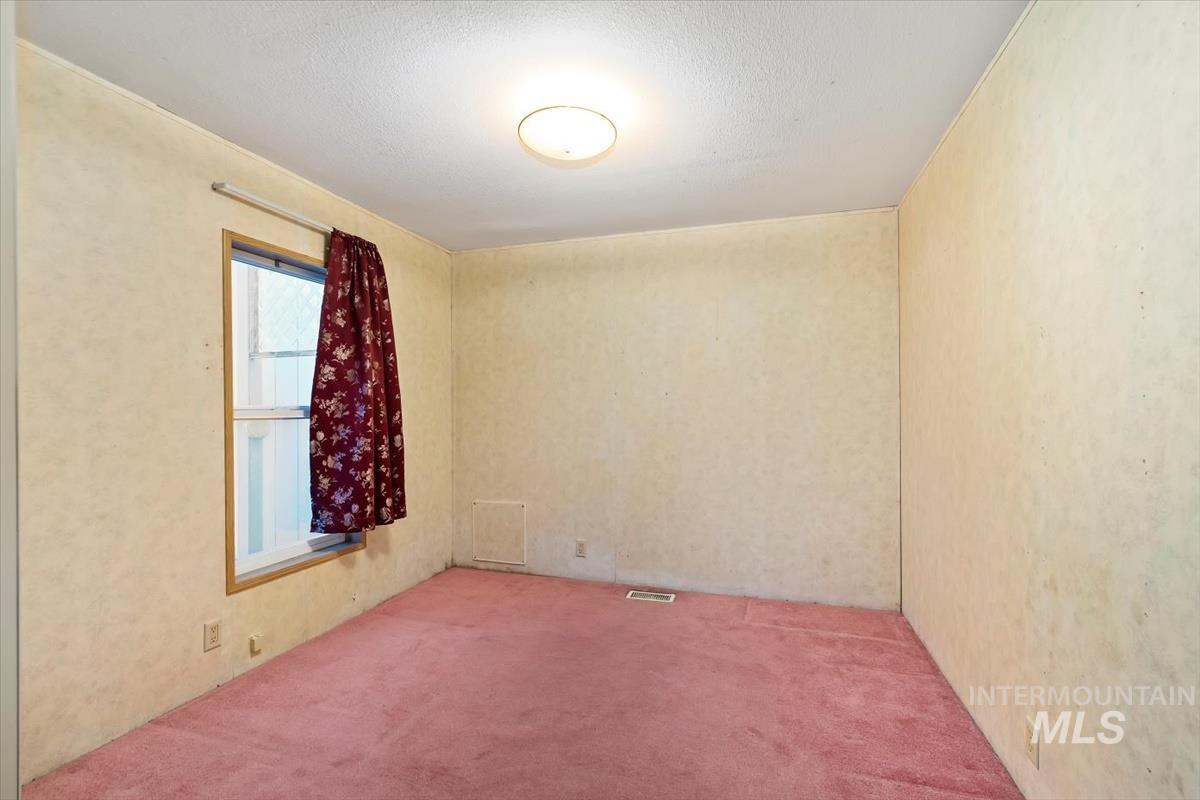 Carpeted empty room with a textured ceiling
