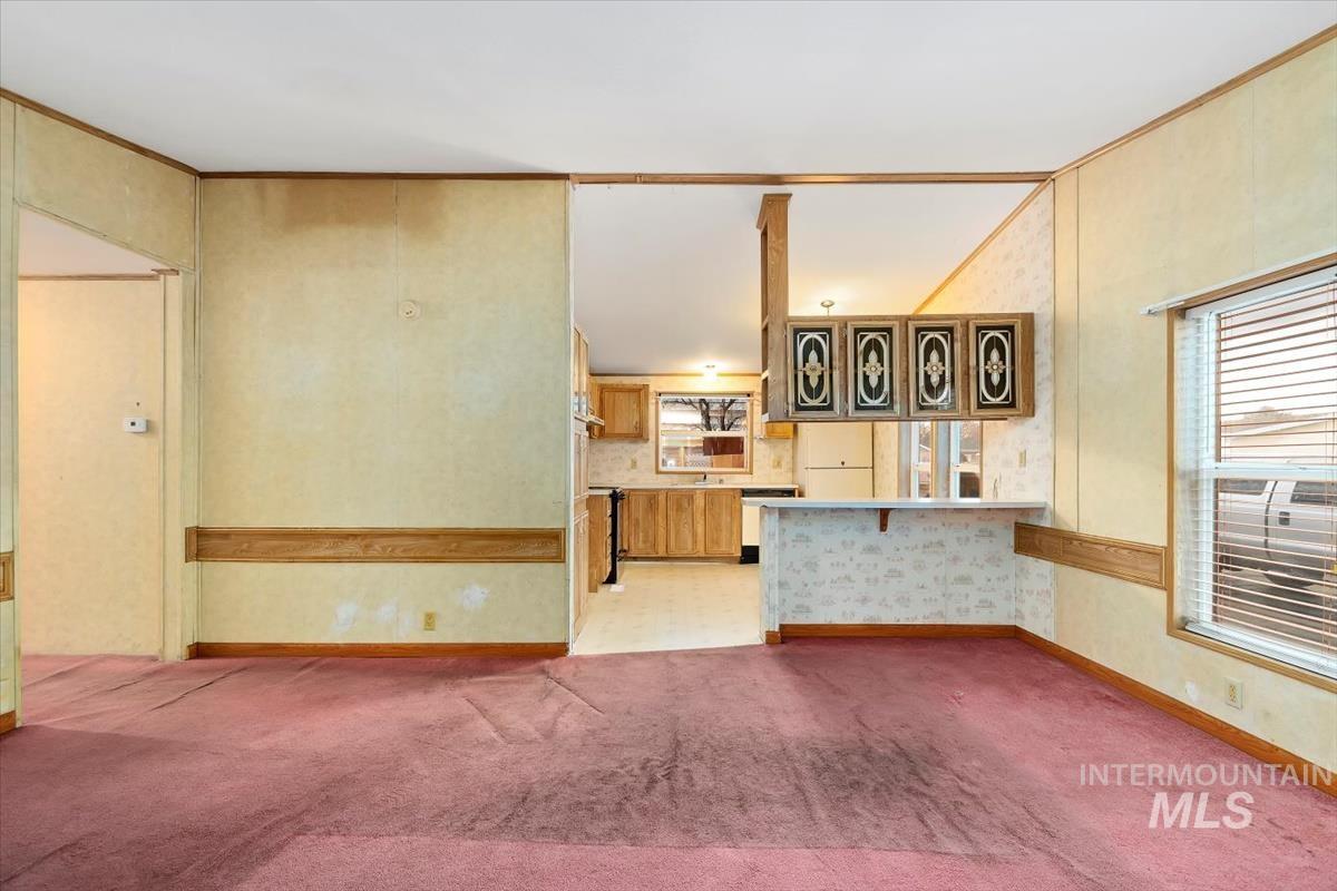 Unfurnished living room with crown molding and light carpet
