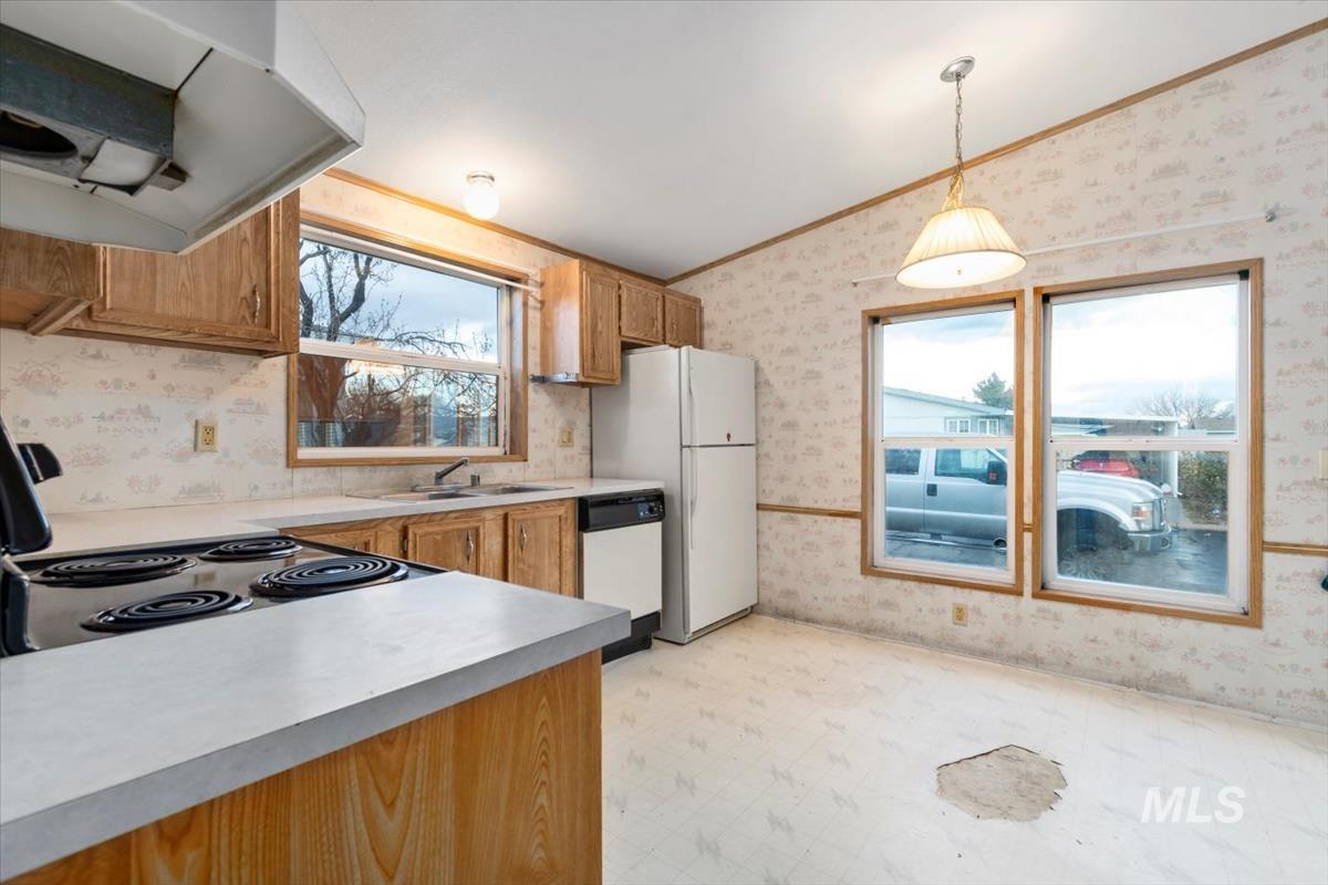 Kitchen featuring wallpapered walls, ventilation hood, brown cabinets, light floors, and pendant lighting
