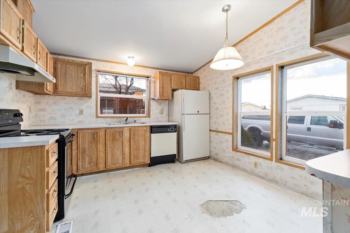 Kitchen with wallpapered walls, light floors, black range with electric stovetop, light countertops, and pendant lighting