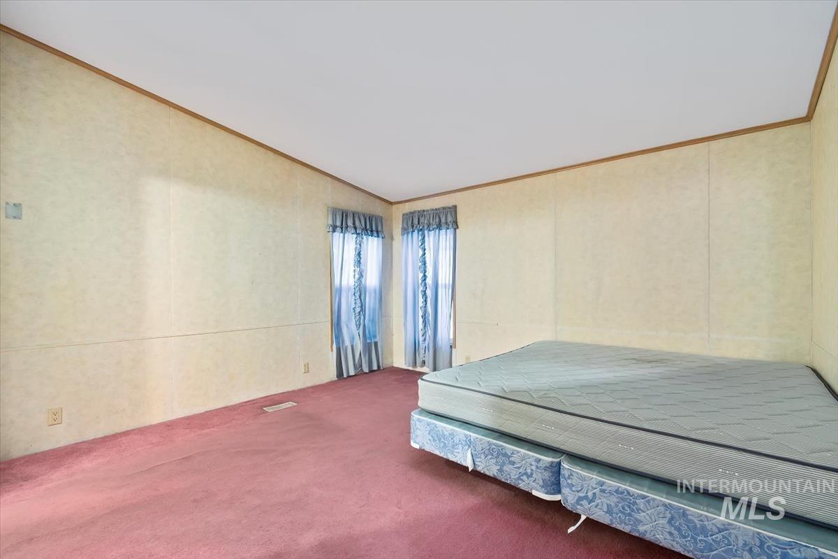 Bedroom featuring carpet, ornamental molding, and vaulted ceiling