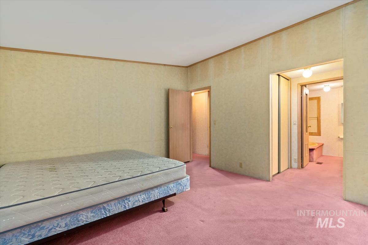 Carpeted bedroom featuring crown molding and connected bathroom