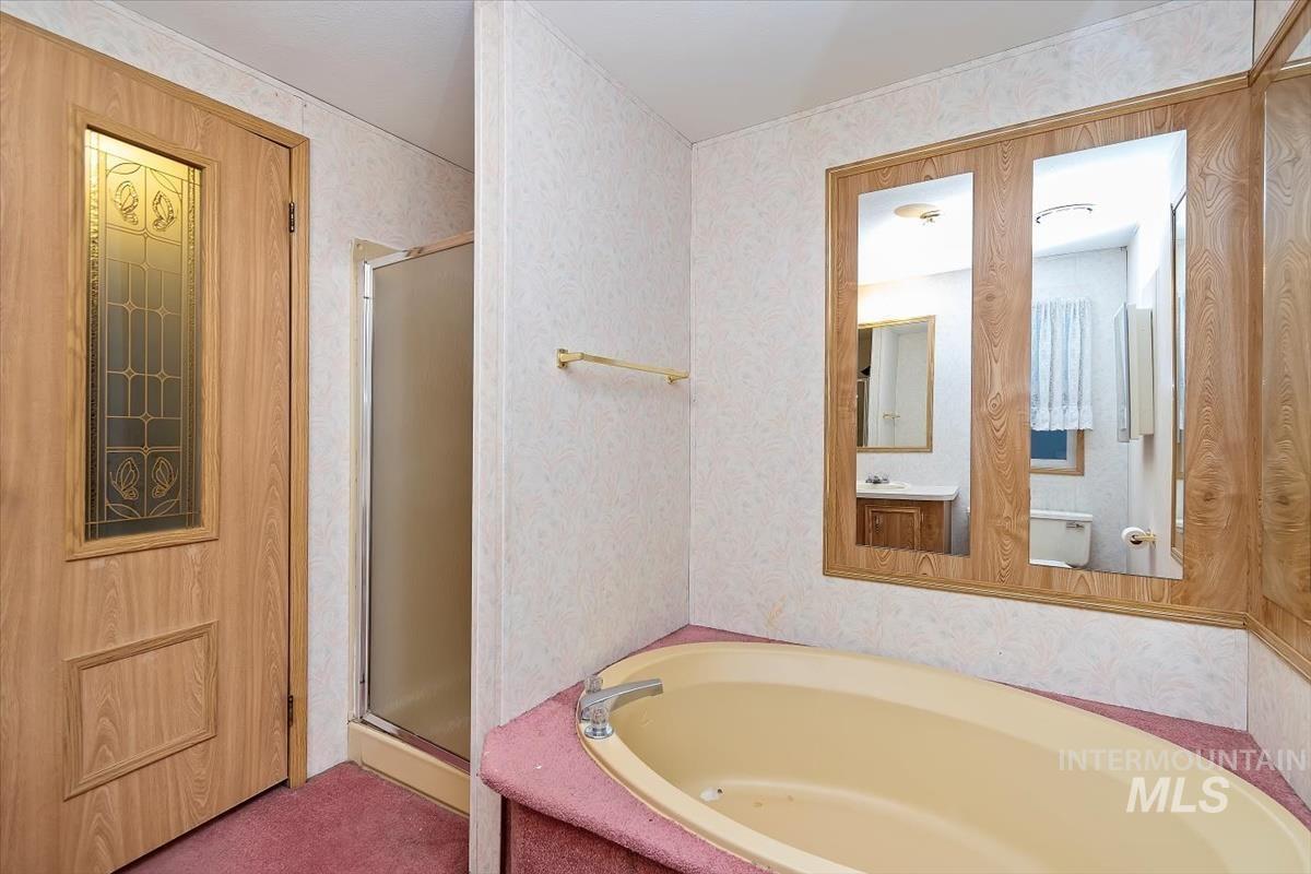 Bathroom with a stall shower, a garden tub, and wallpapered walls