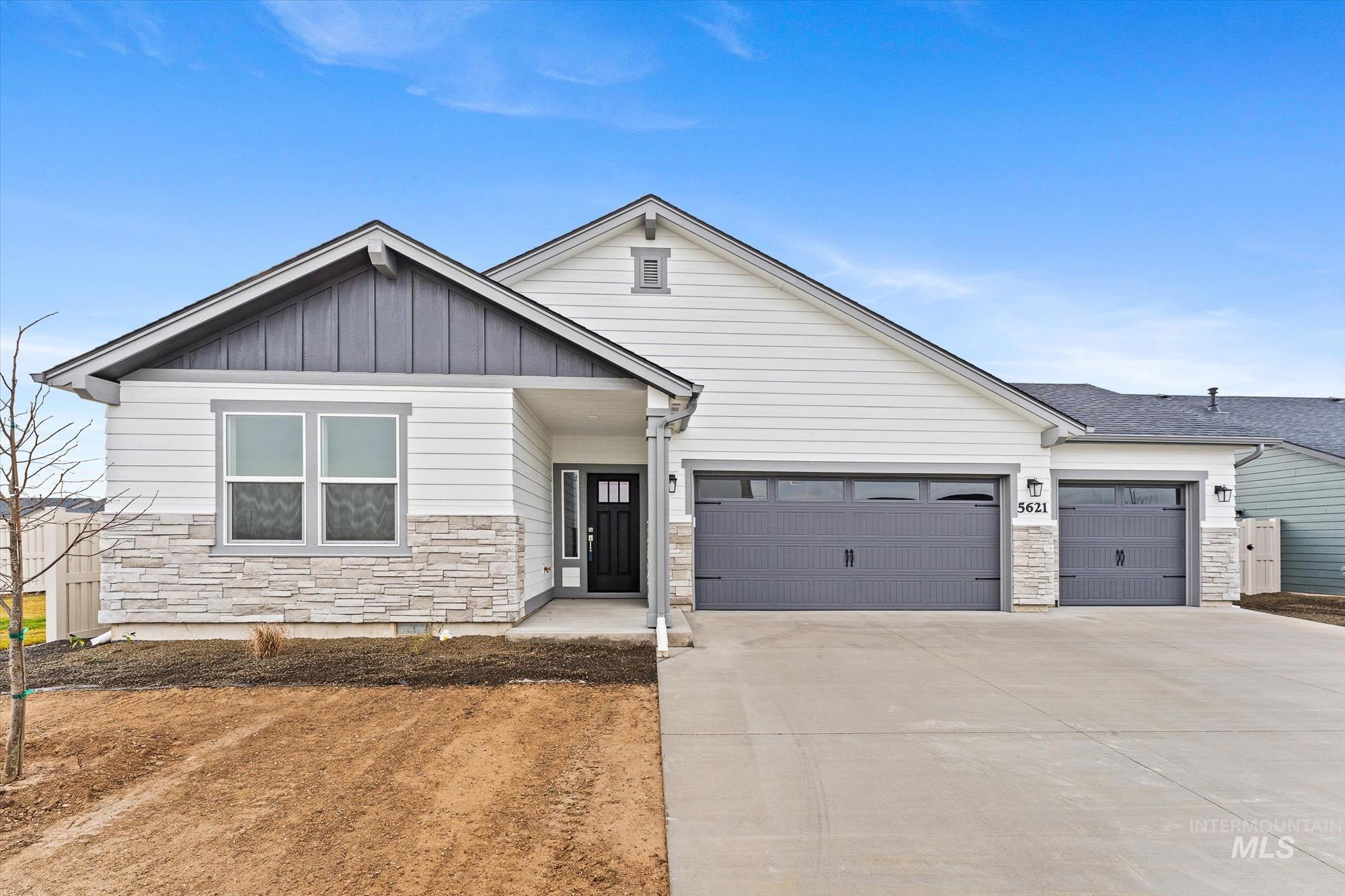View of front of home with stone siding, board and batten siding, concrete driveway, and a garage