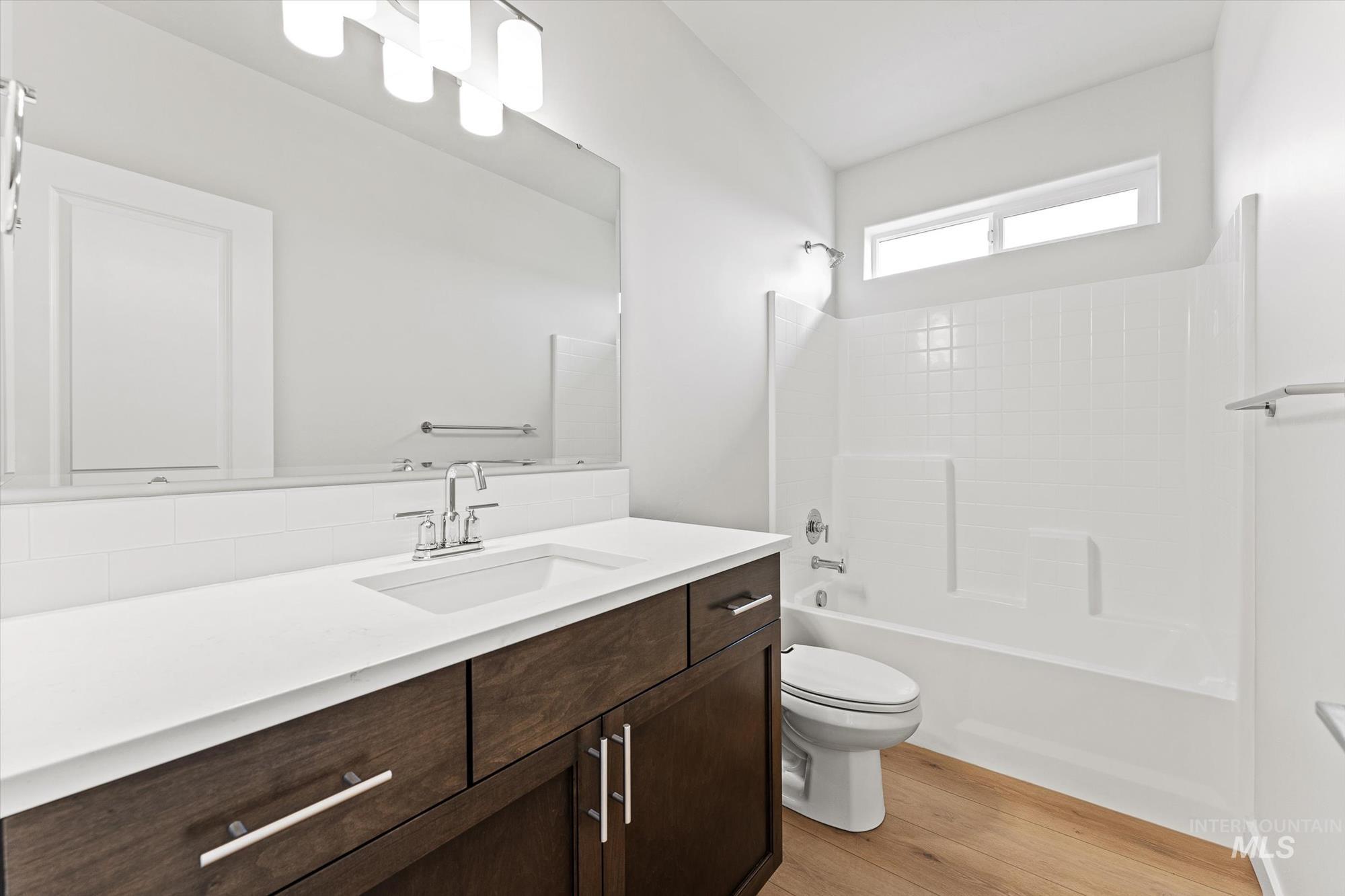 Bathroom with shower / bath combination, vanity, and light wood-style flooring