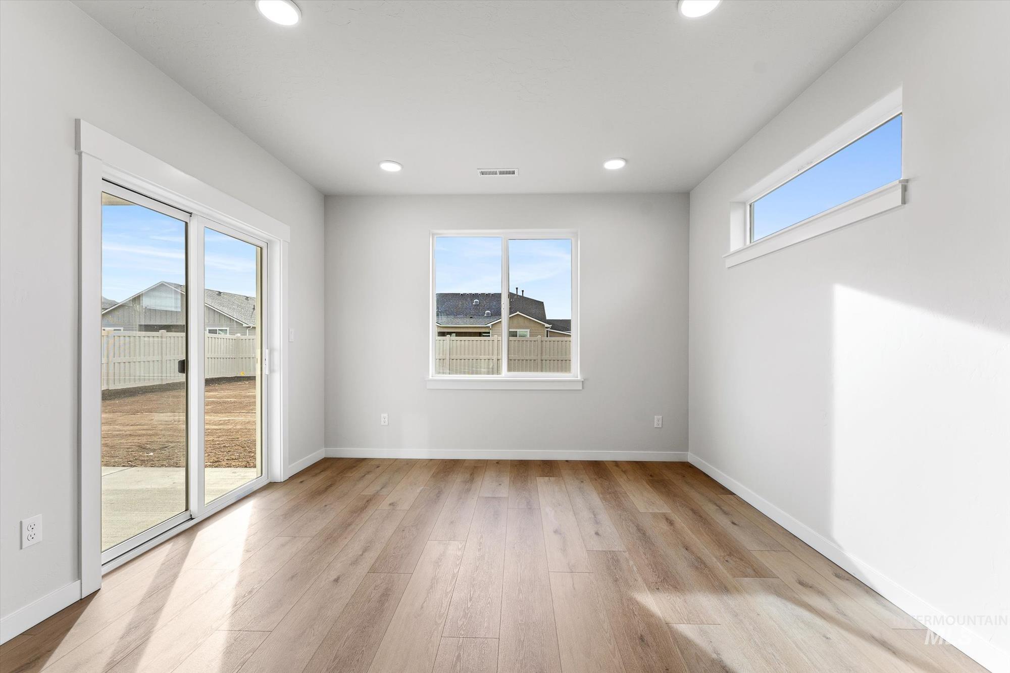 Empty room with light wood-style floors and recessed lighting