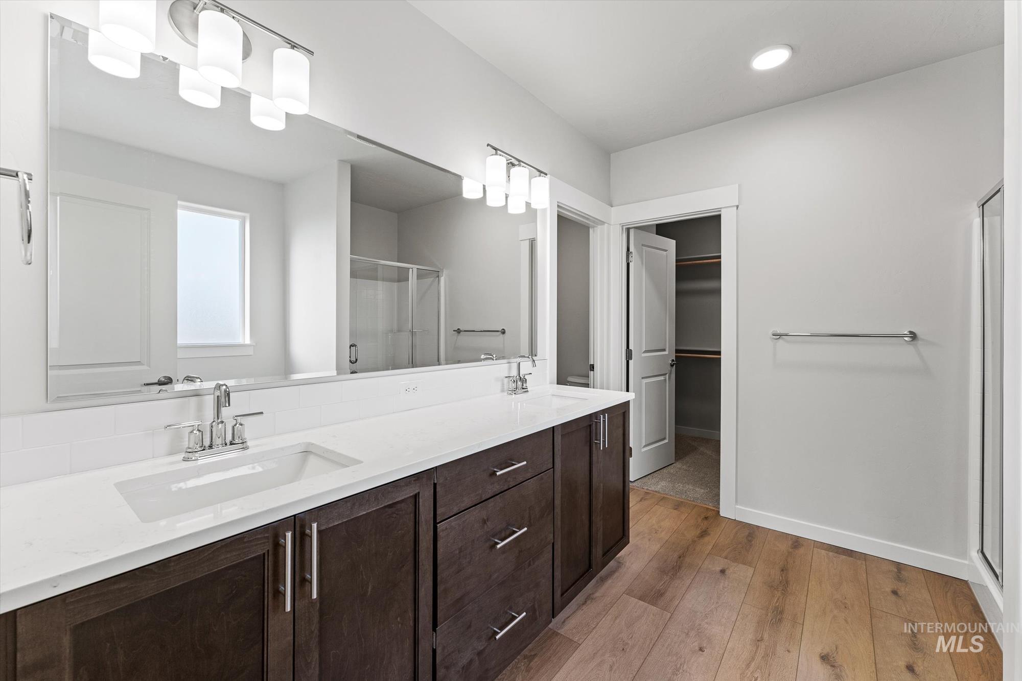 Bathroom with a stall shower, double vanity, light wood-style floors, and a spacious closet