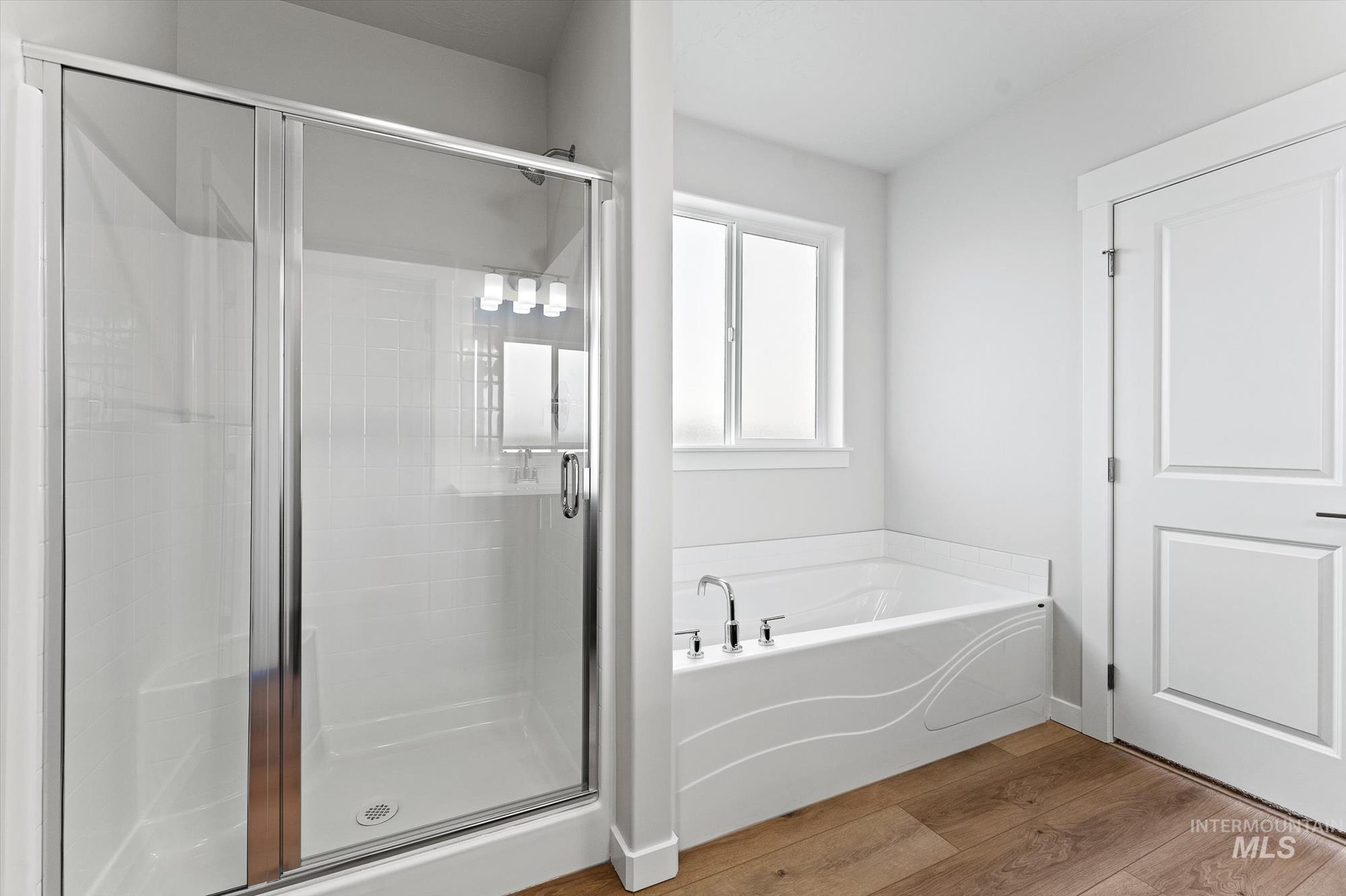 Full bathroom with a bath, light wood-style flooring, and a stall shower