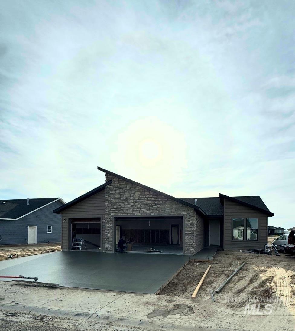 View of front of property with driveway, an attached garage, and stone siding